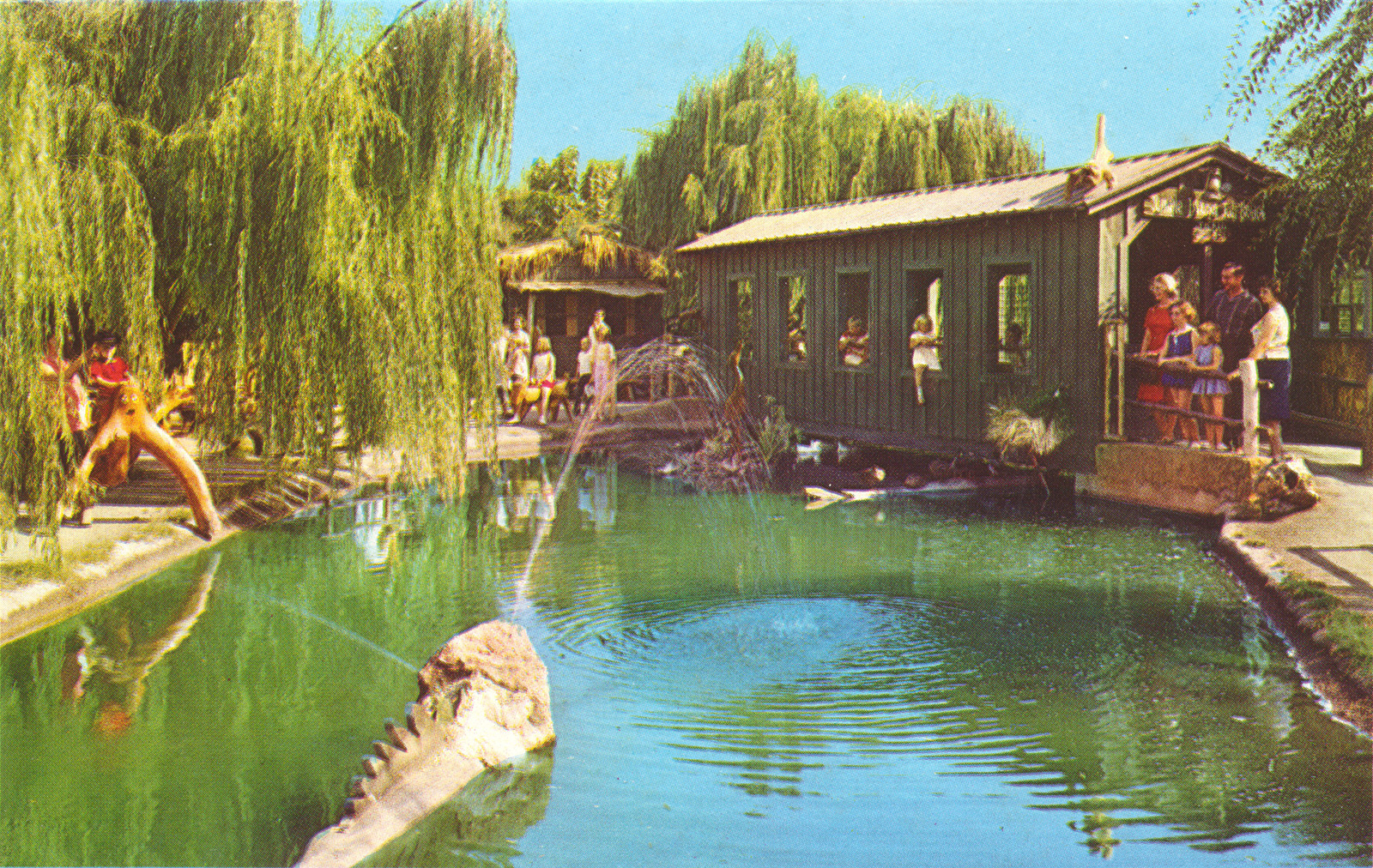 Jungle Island. A covered bridge is over a body of water, weird wood creatures are on the shore.