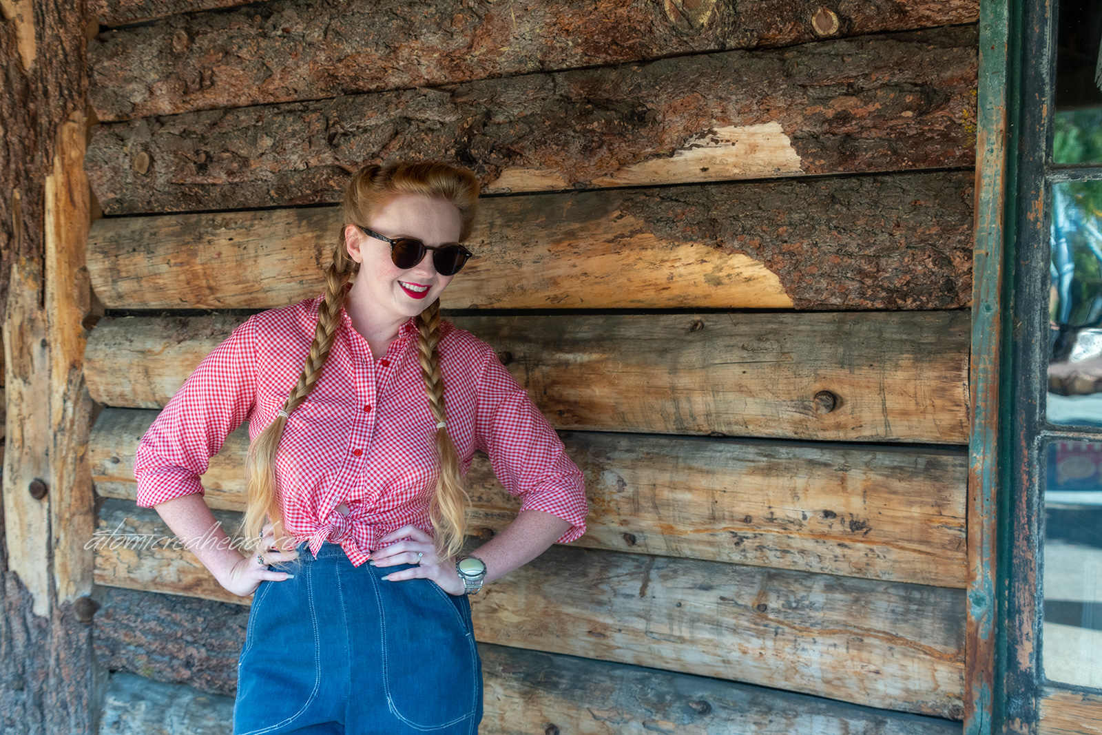 Myself standing in front of a building made of logs, wearing a red and white gingham shirt, and blue jeans.
