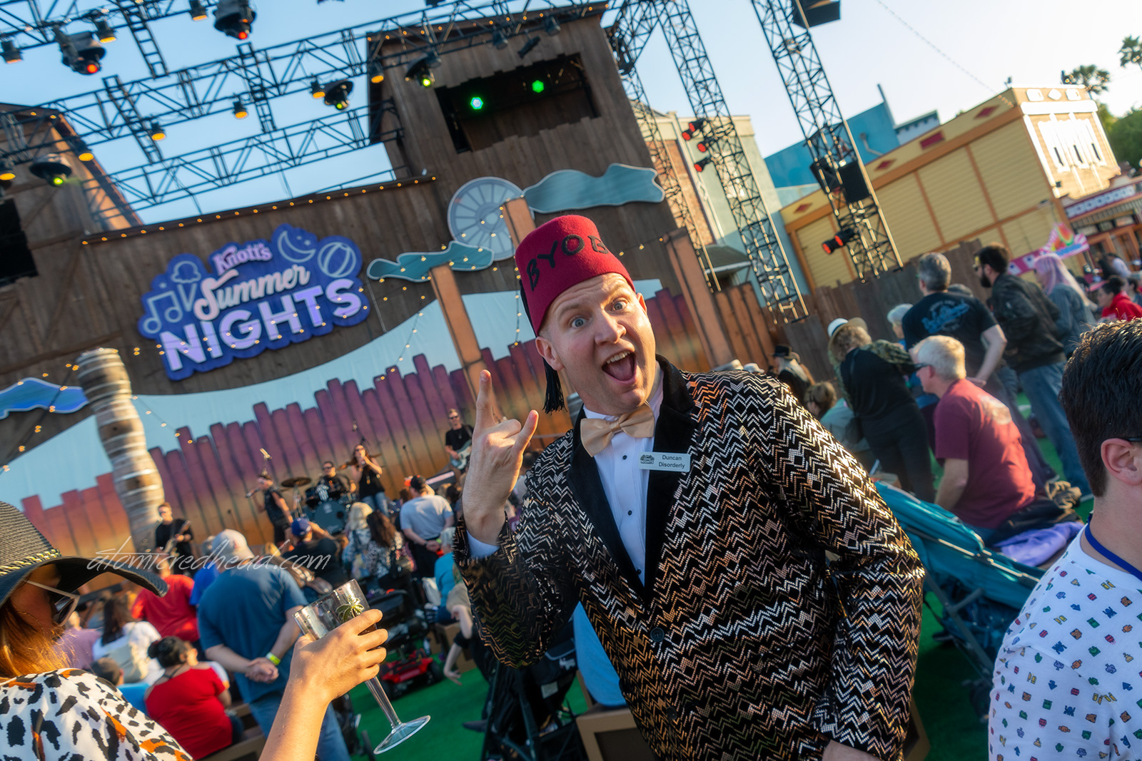 The head of the party planning committee, Duncan Disorderly, wearing a red fez, and gold and black tuxedo jacket, dances to the live music.