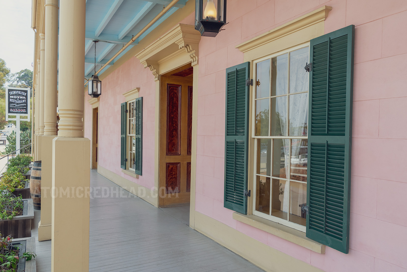Exterior promenade, pink walls, green shutters, and pale yellow trim around the doors and windows. 