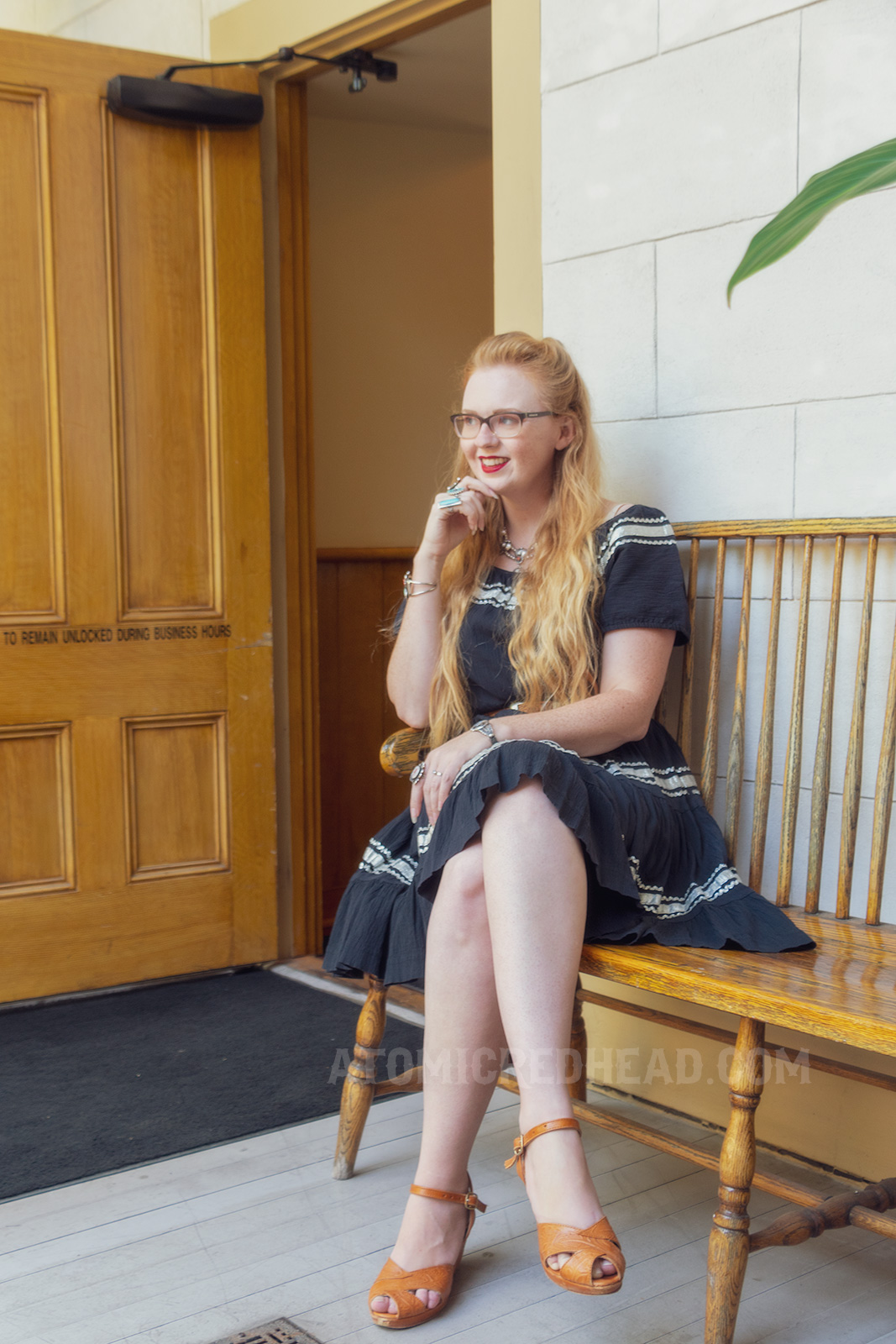 Myself sitting on an outside bench wearing a black dress with silver trim.
