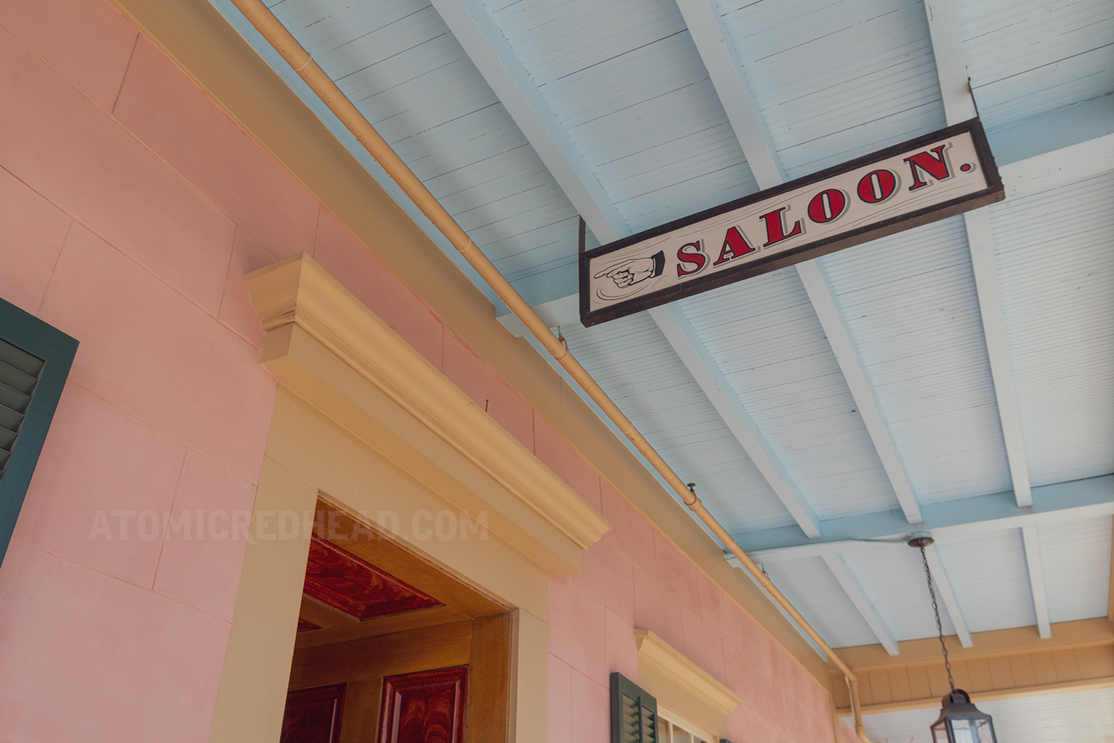 A white sign with red letters reads "Saloon" with a hand painted pointed the way.