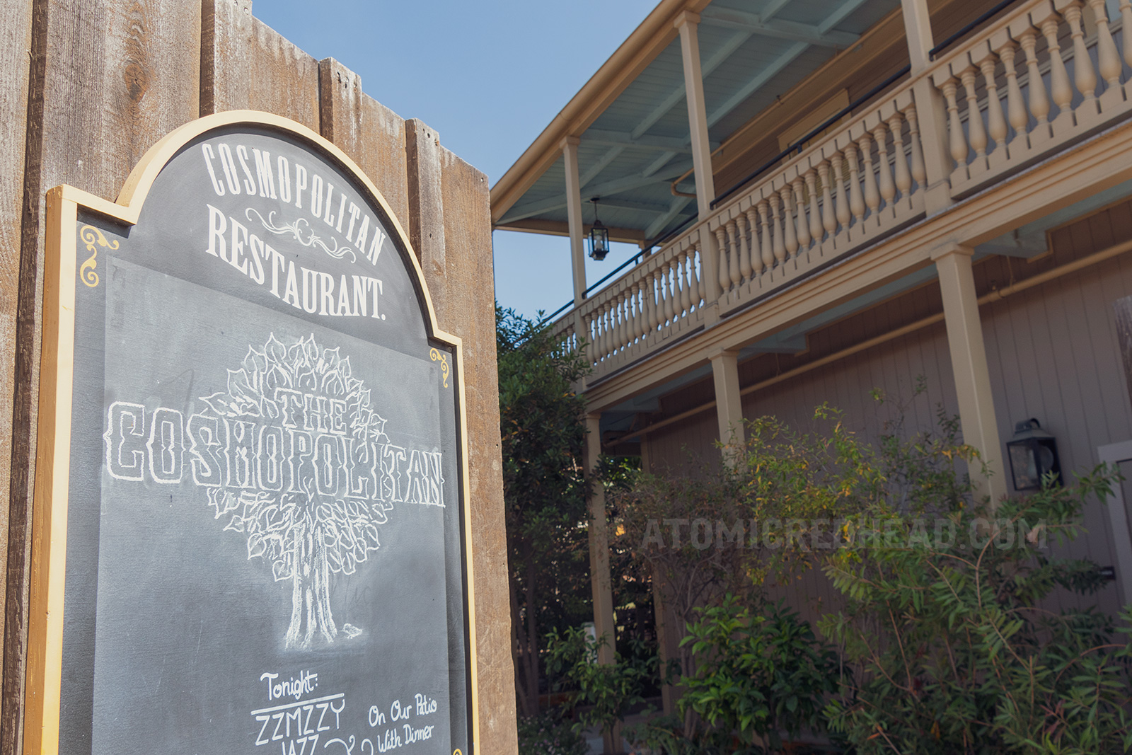 A chalkboard hangs on a wooden door to the courtyard, reading "Cosmopolitan"