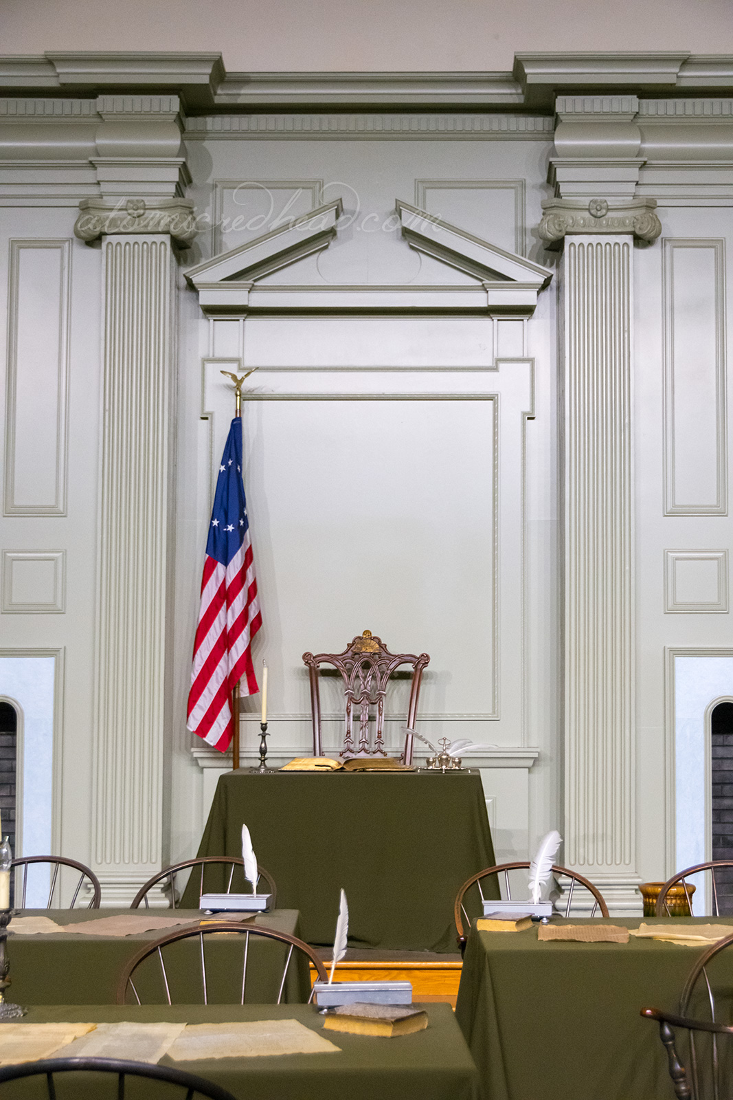 Inside the singing room, a chair and small desk sit against the back wall. The walls are painted a pale green color.
