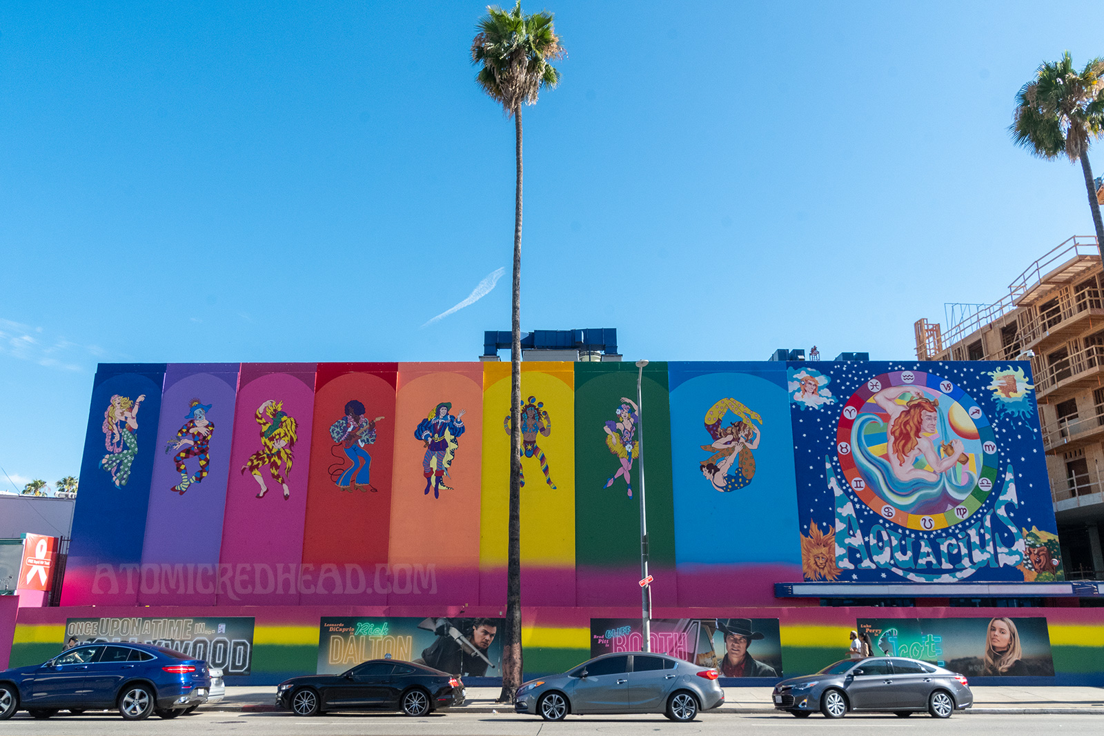A rainbow paint job covers the former Earl Carroll. Panels, each a different color, feature psychedelic characters, including dancers, musicians, acrobats, and jugglers. A massive painting of a nude man with long red hair pouring water from pitchers is painted on the right side, icons of astrology circle him. "Aquarius" is painted below him.
