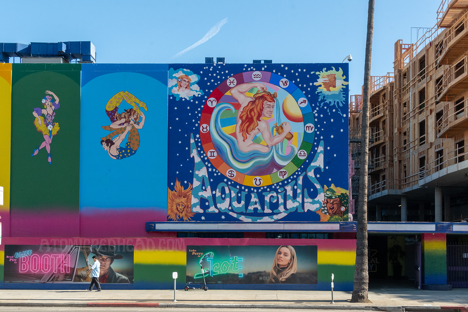 A rainbow paint job covers the former Earl Carroll. Panels, each a different color, feature psychedelic characters, including dancers, musicians, acrobats, and jugglers. A massive painting of a nude man with long red hair pouring water from pitchers is painted on the right side, icons of astrology circle him. "Aquarius" is painted below him.