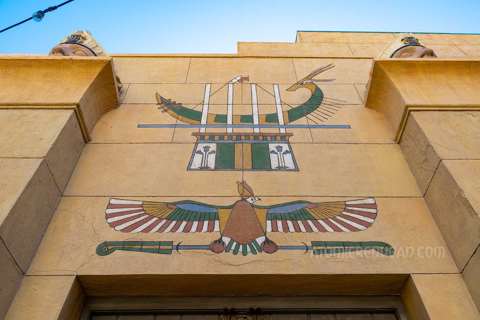 A mural of a hawk and a boat above the pair of wooden doors.