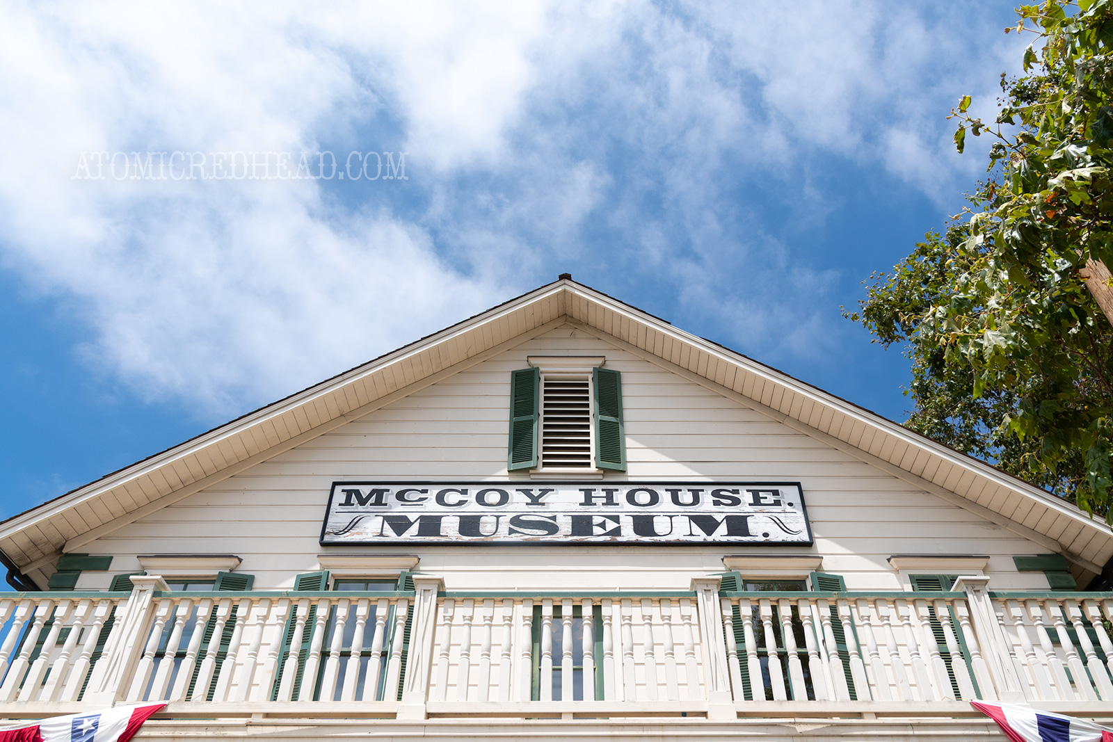 The exterior of the McCoy House, a simple two story house painted white with green shutters.