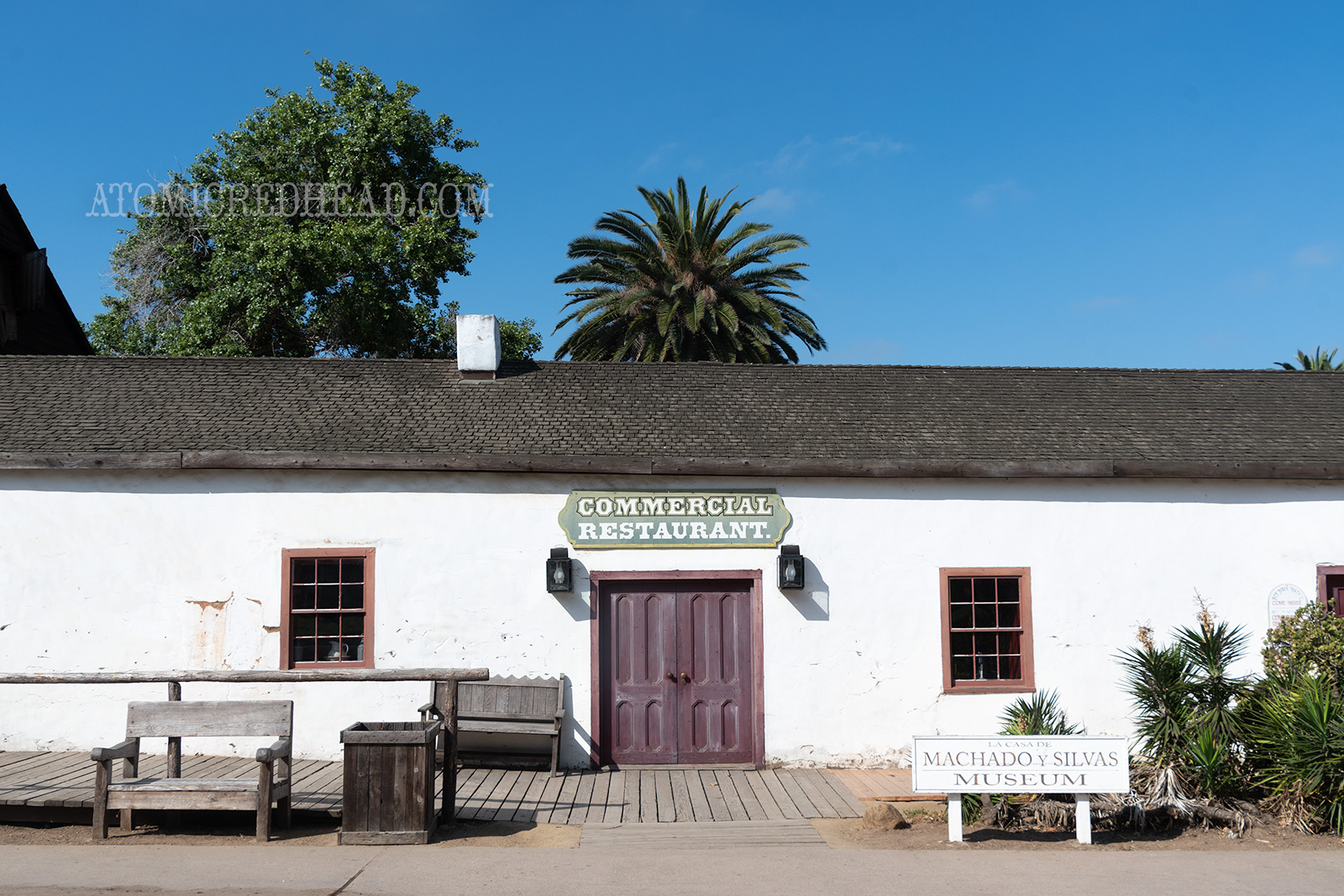 Exterior of the Commercial Restaurant. A single story adobe building with dark maroon doors.