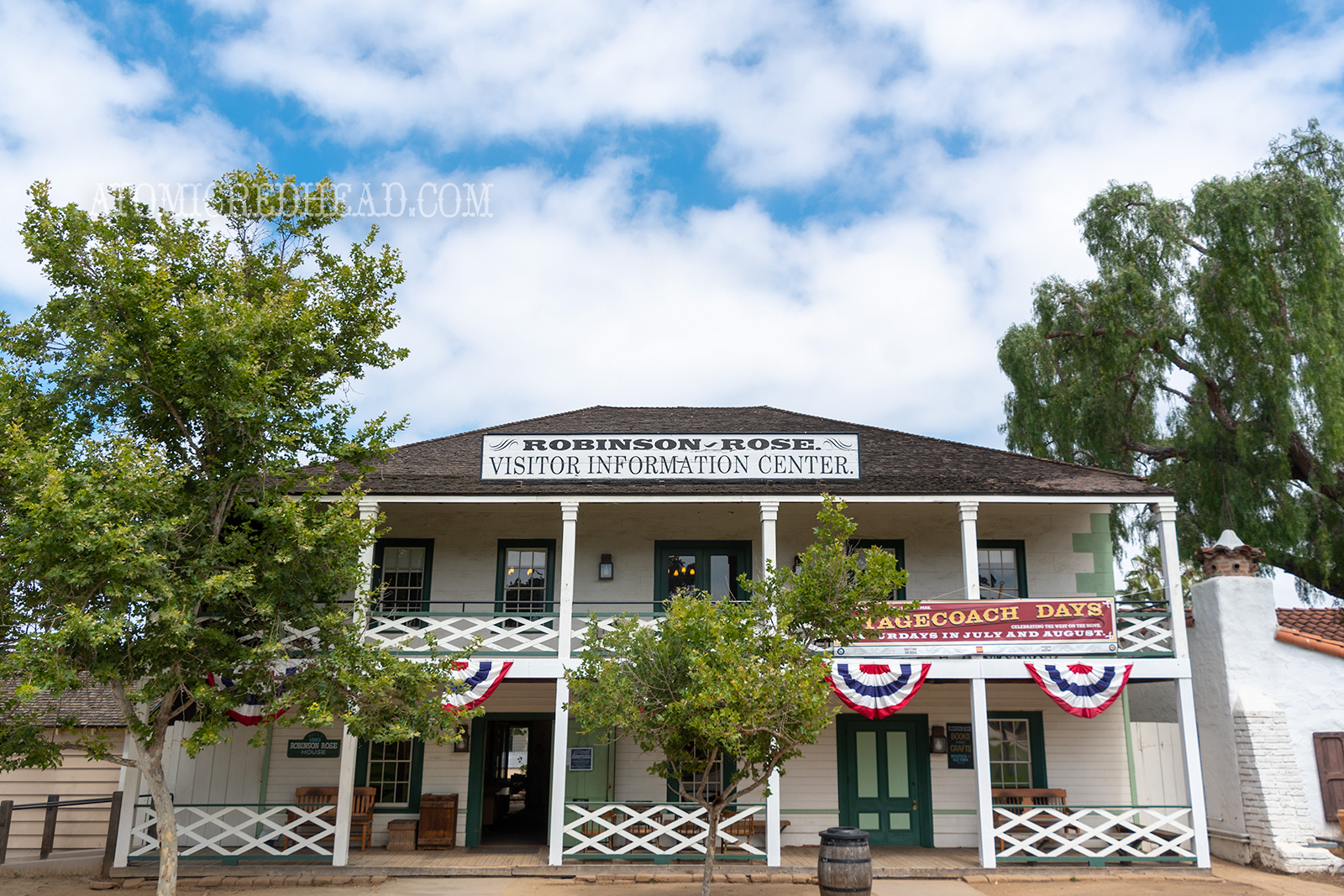The Robinson Rose House, an old two story home, with porch and balcony, painted white with green doors and window frames.