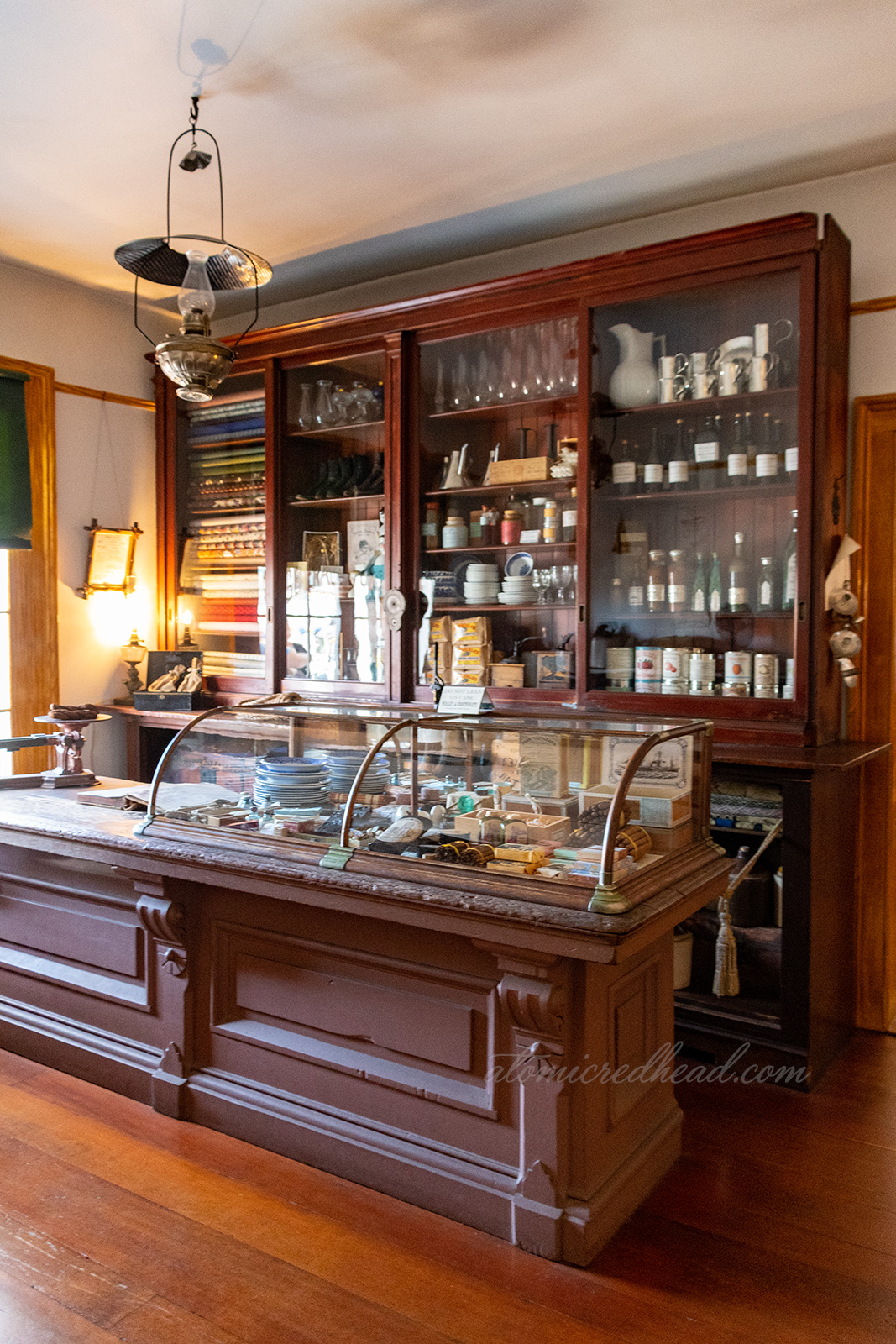 Area of the home that was Whaley's general store. Dark wood display cases feature various items from the era.
