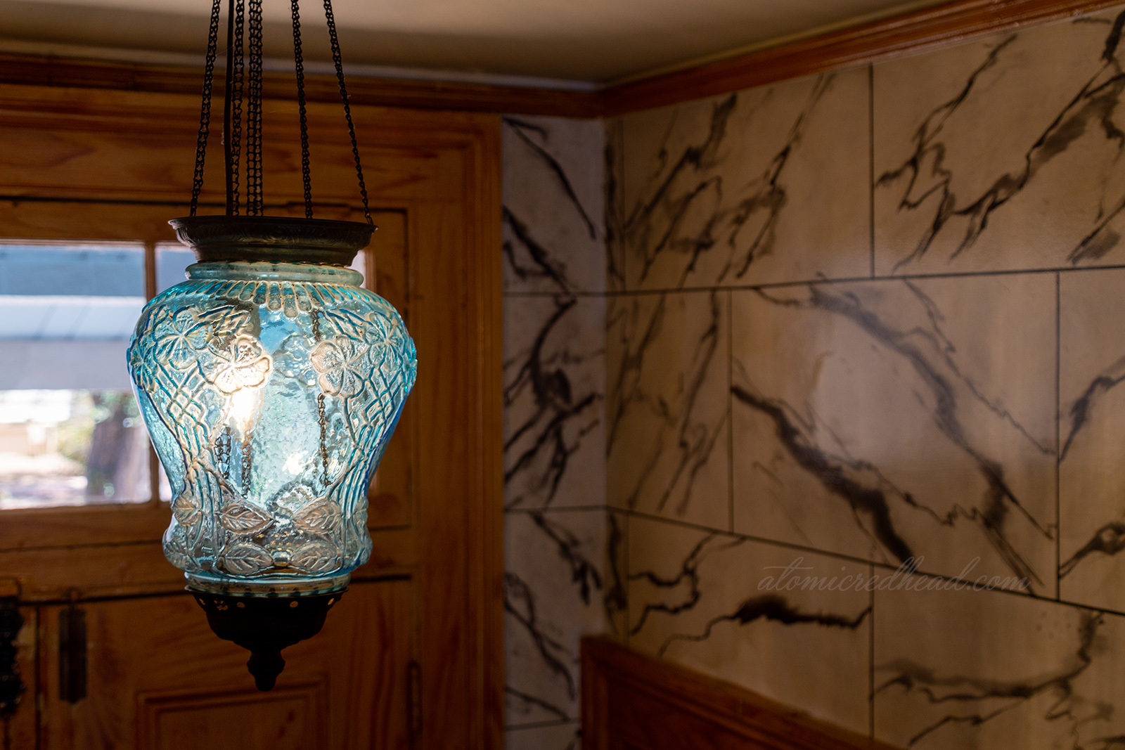A blue glass light fixture featuring a floral motif hangs in the hallway.