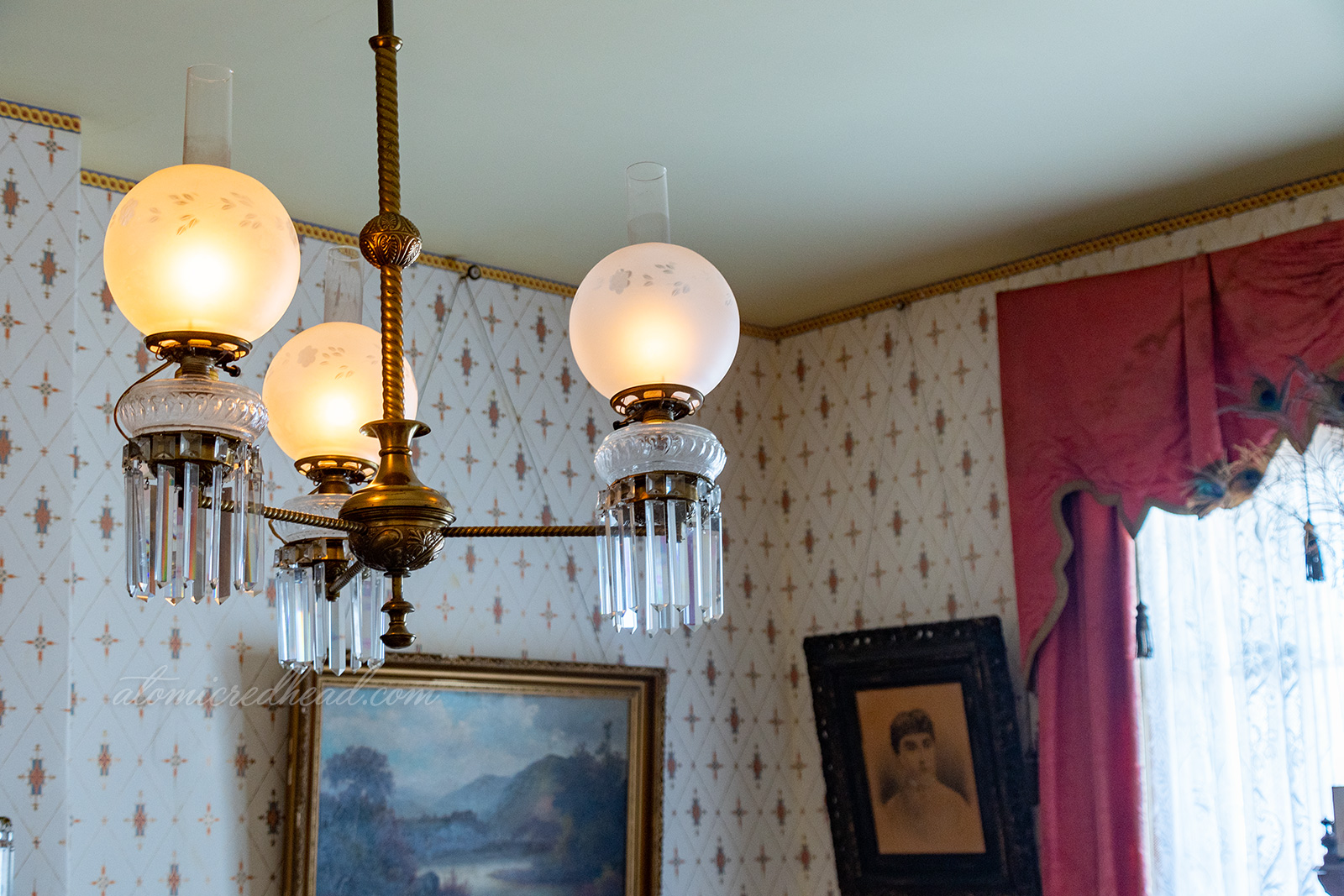 The light fixture of the parlor, three glass globes with crystals hanging below.