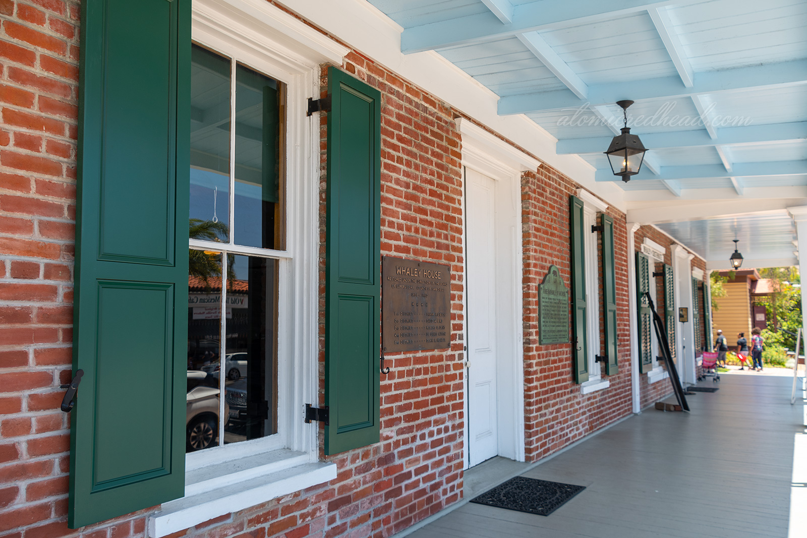The porch of the home, which is brick, with green shutters.