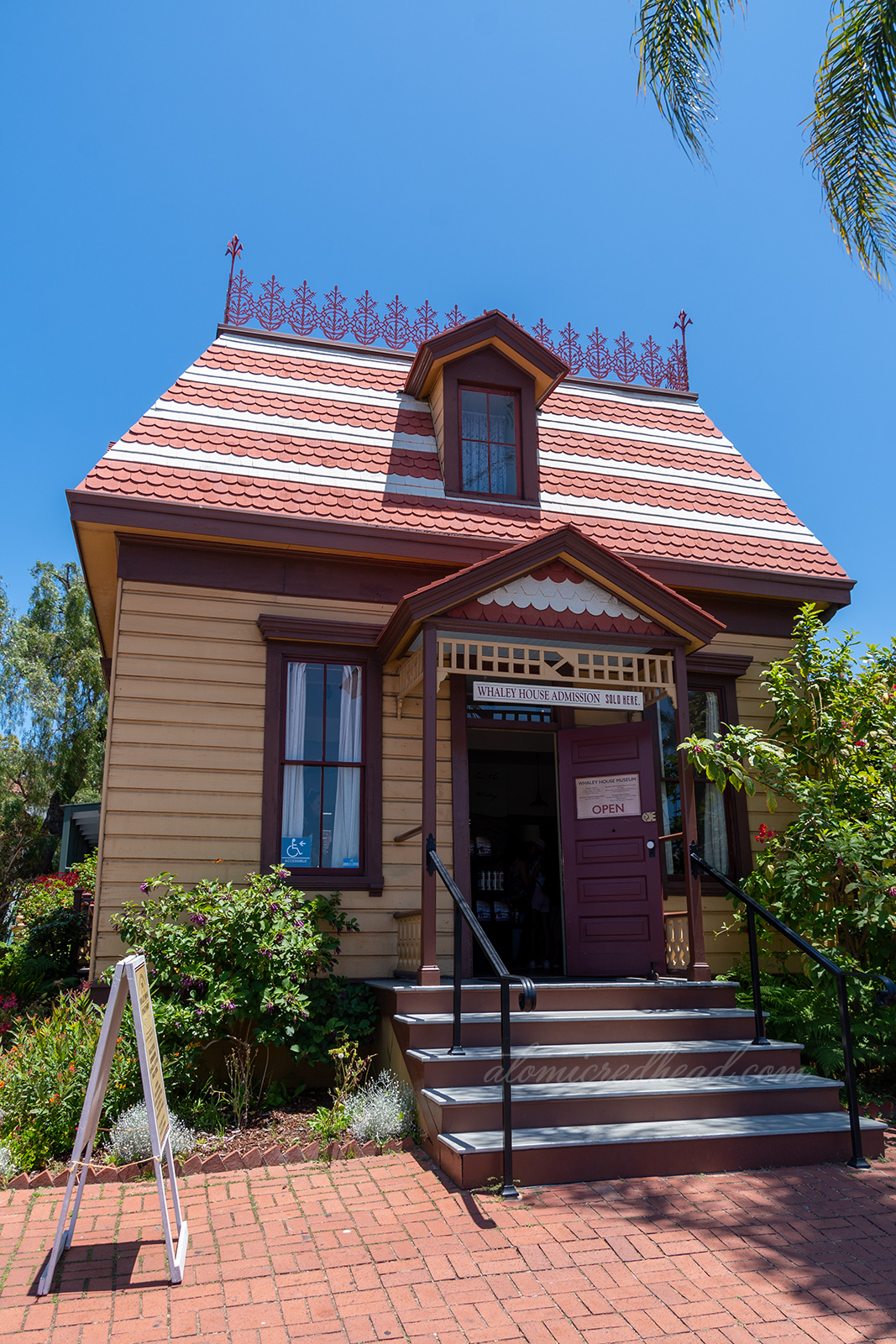 The Verna House, a small home painted a golden yellow and maroon.