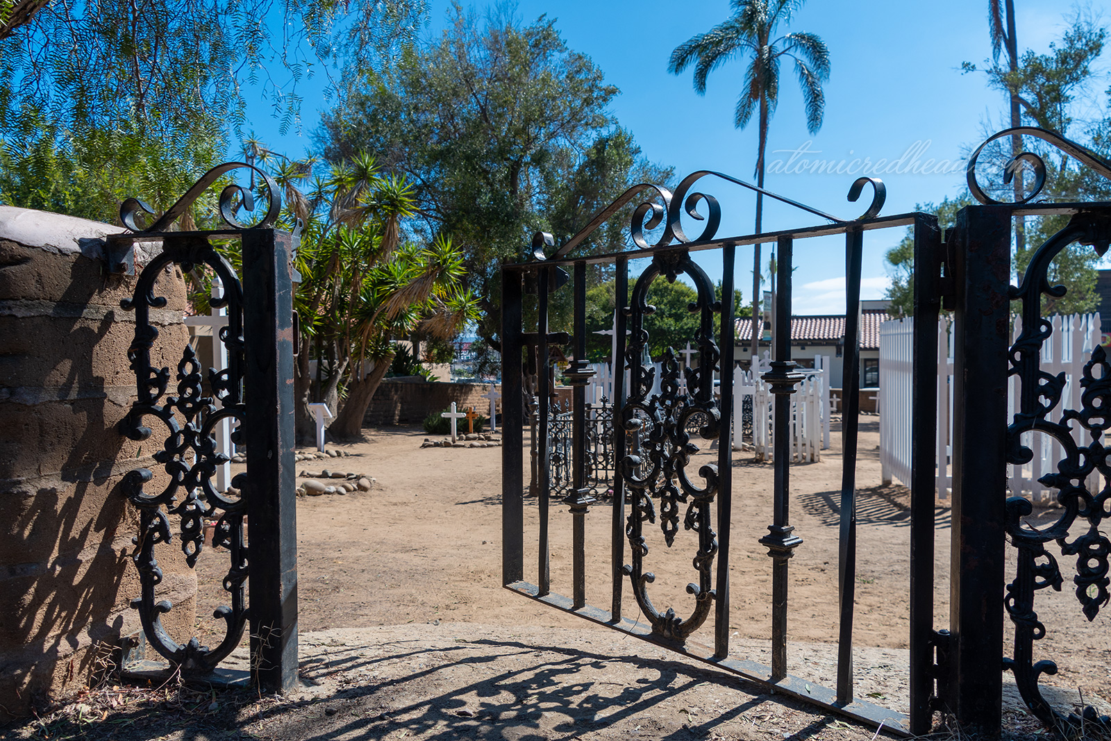 A black wrought iron gate opens into the cemetery.