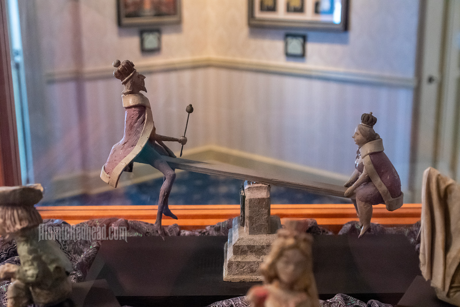 A small statue of a king and queen on a see-saw.