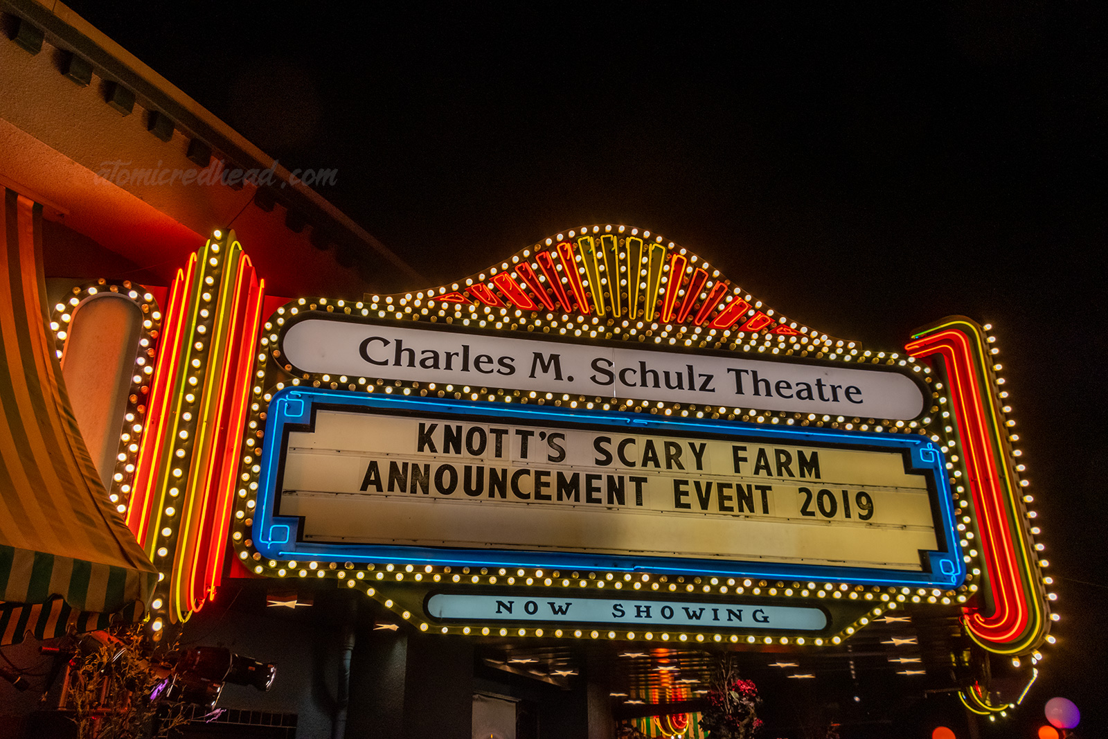 The neon sign for the Charles M. Schulz Theatre, with yellow and red neon and the marquee reads "Knott's Scary Farm Announcement Event 2019"