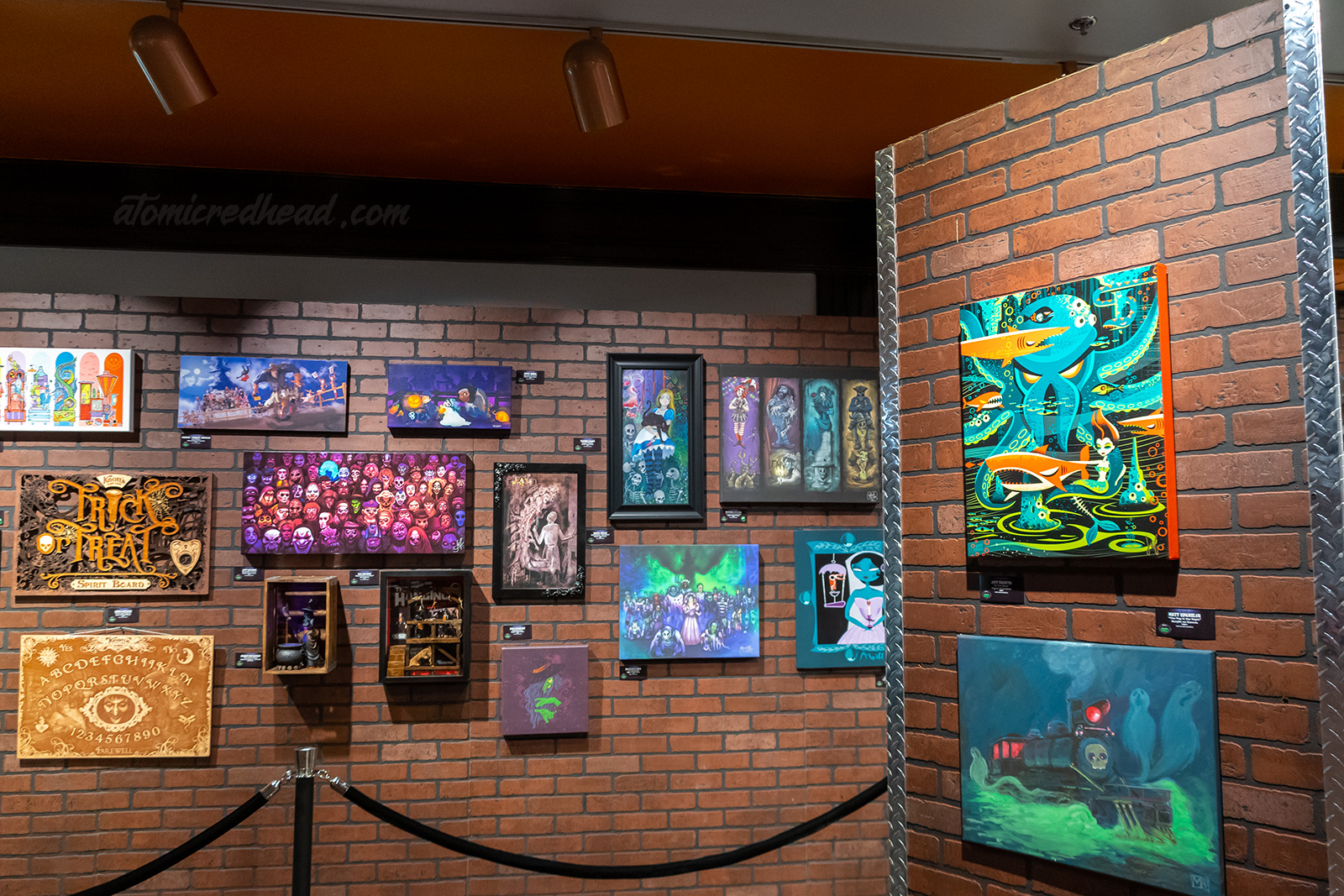 Various works of art depicting Scary Farm monsters hang on a brick wall.