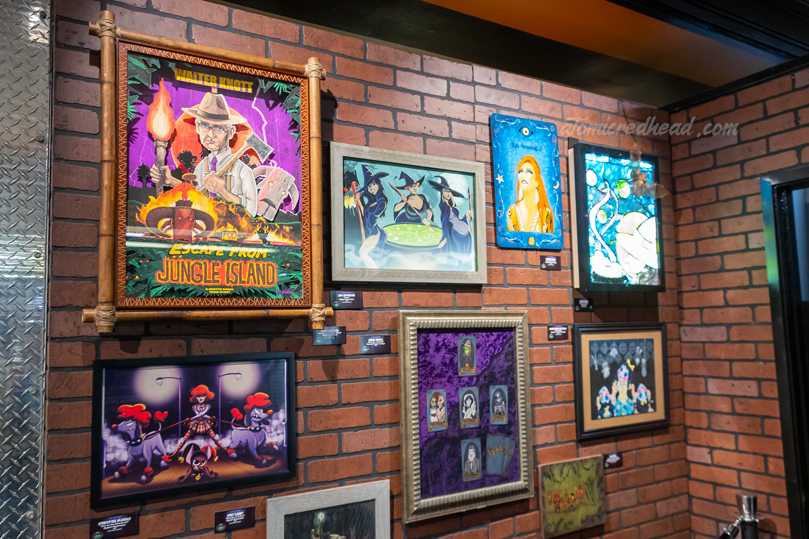 Various works of art depicting Scary Farm monsters hang on a brick wall.