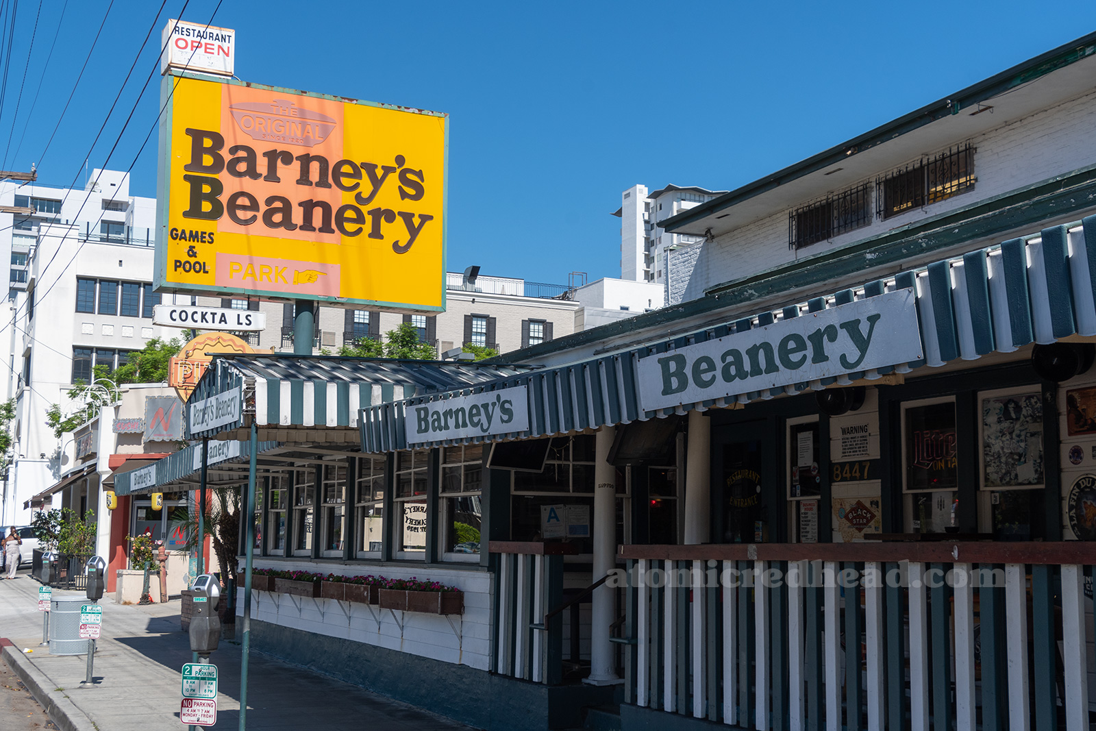 Exterior of Barney's Beanery, a two story California Craftsman painted green and white, with an orange and yellow sign reading "The Original Barney's Beanery Games & Pool"