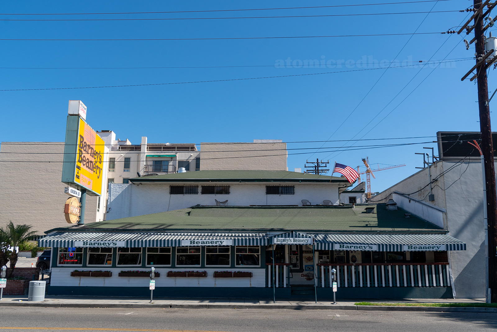 Exterior of Barney's Beanery, a two story California Craftsman painted green and white, with an orange and yellow sign reading "The Original Barney's Beanery Games & Pool"