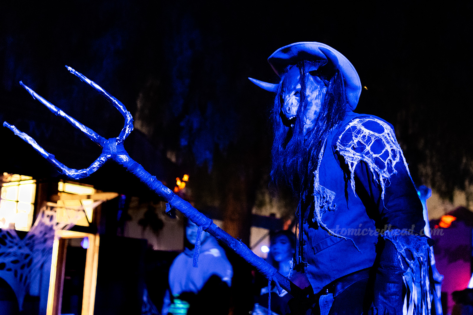 A tall, half-bull, half-human cowboy carrying a massive pitchfork walks through Ghost Town.