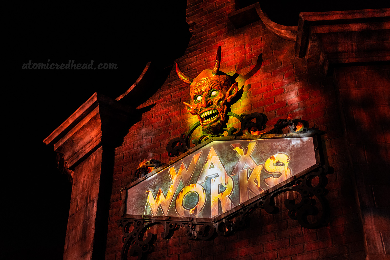 The entrance to Wax Works, a brick building with a devil head above the sign reading "Wax Works"