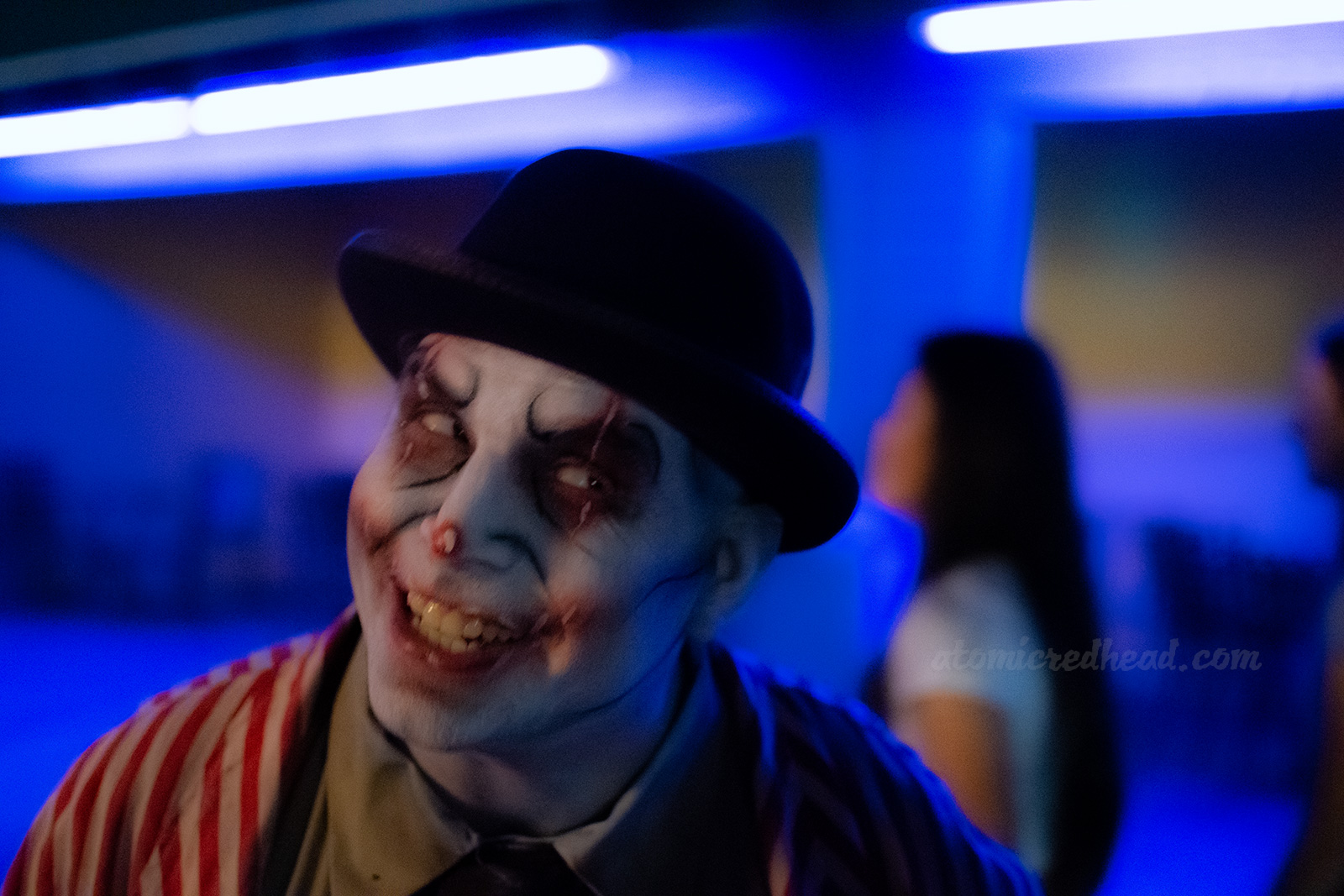 A clown in classic white make-up and a bowler hat leers toward guests