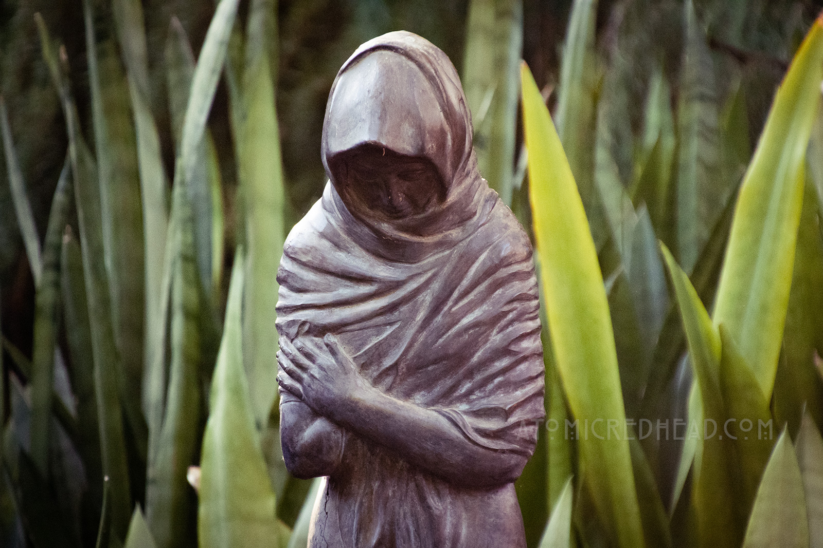 A statue of a hooded figure with their arms crossed.