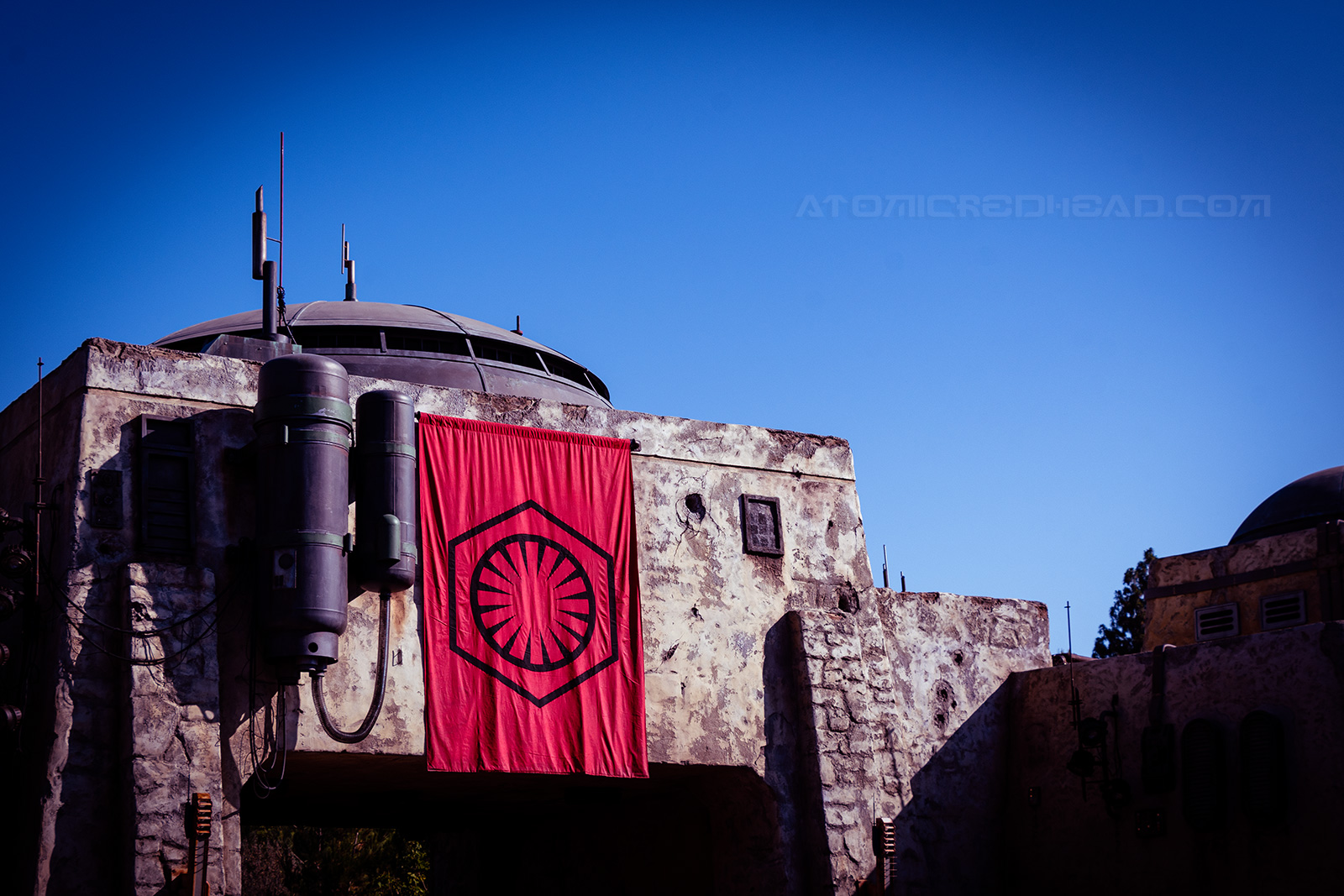 A red and black First Order banner hangs from a grey building with a domed roof.