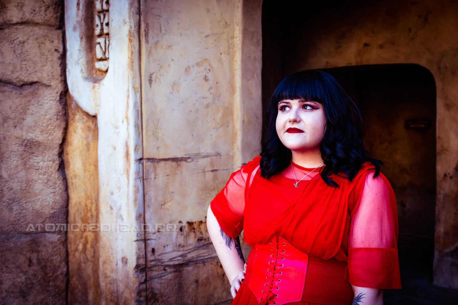 Brittany wears a sheer crimson dress with a corset belt.