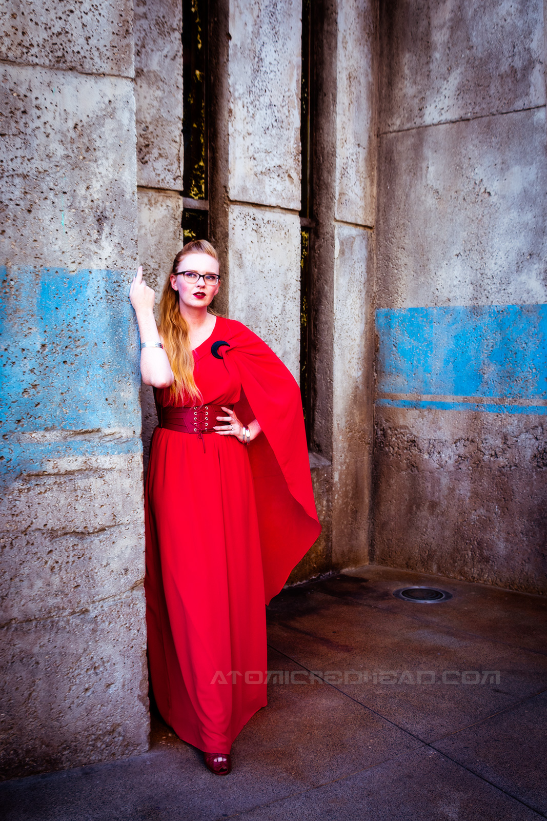 Myself wearing a full length red gown, it is asymmetrical with one shoulder ending in a short cape. A corset style belt at my waist, and a black crescent moon brooch at the shoulder.