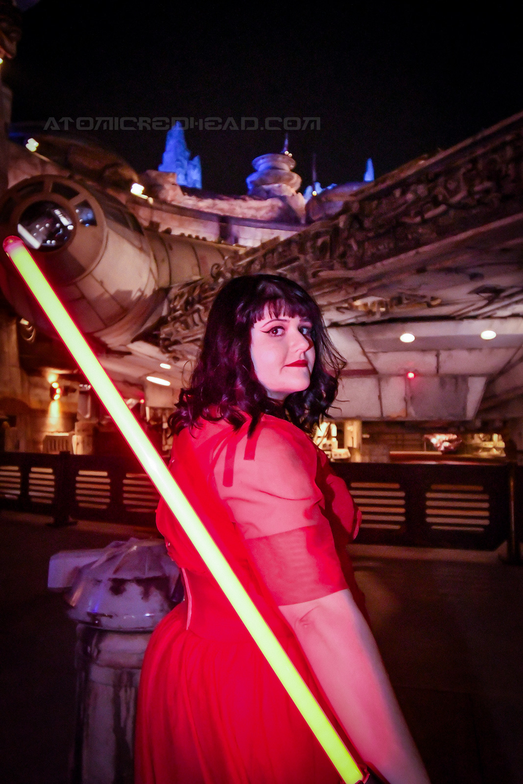 Brittany holds a red light saber near the Falcon.
