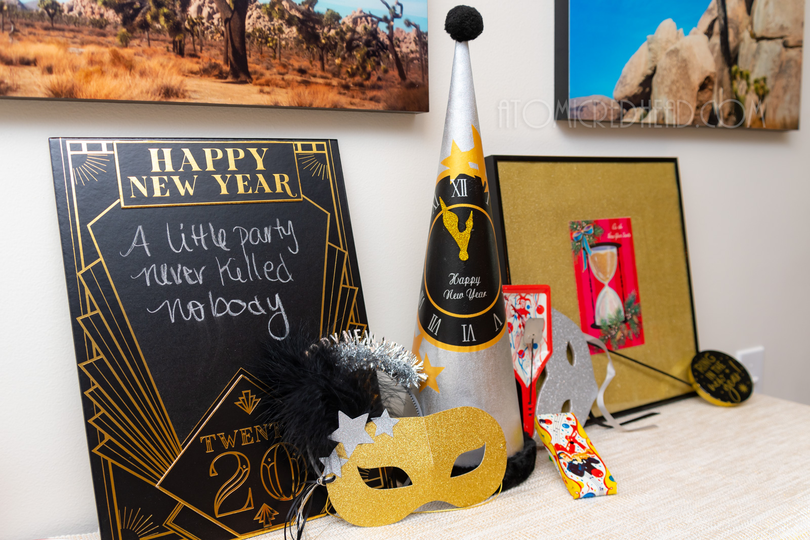Close-up of a silver hat with a black and gold clock, a gold glitter mask, and variety of vintage noise makers.