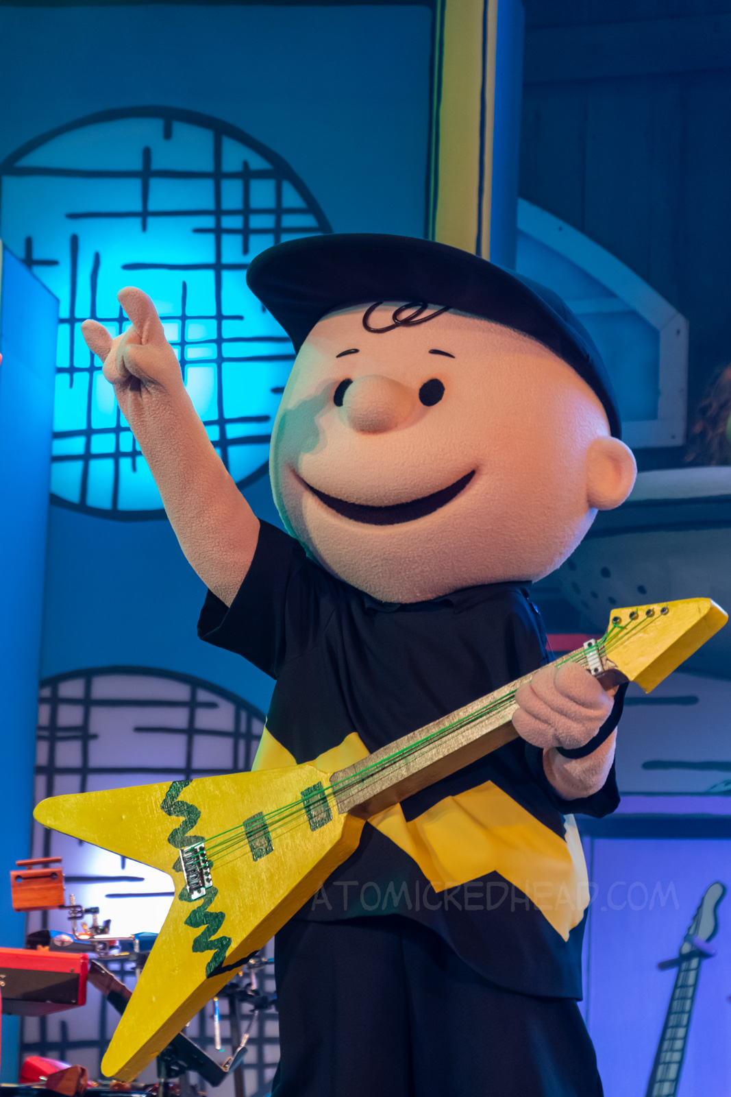 Charlie Brown rocks out at Woodstock's Music Festival, with a guitar featuring his iconic yellow with black zig-zag design.