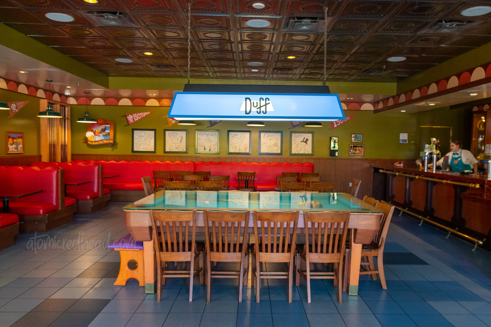 Inside Moe's Tavern, red leather booths, a pool table, and a bar sits off to the right.