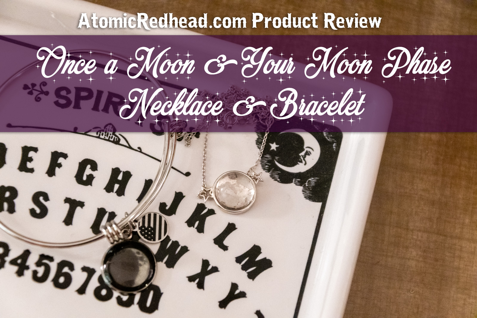 A necklace resembling the full moon, flanked by two silver stars, and a bracelet with an image of a crescent moon as a charm sits in a dish that resembles a spirit board. Overlay text reads "Atomic Redhead Product Review Once a Moon & Your Moon Phase Necklace & Bracelet"