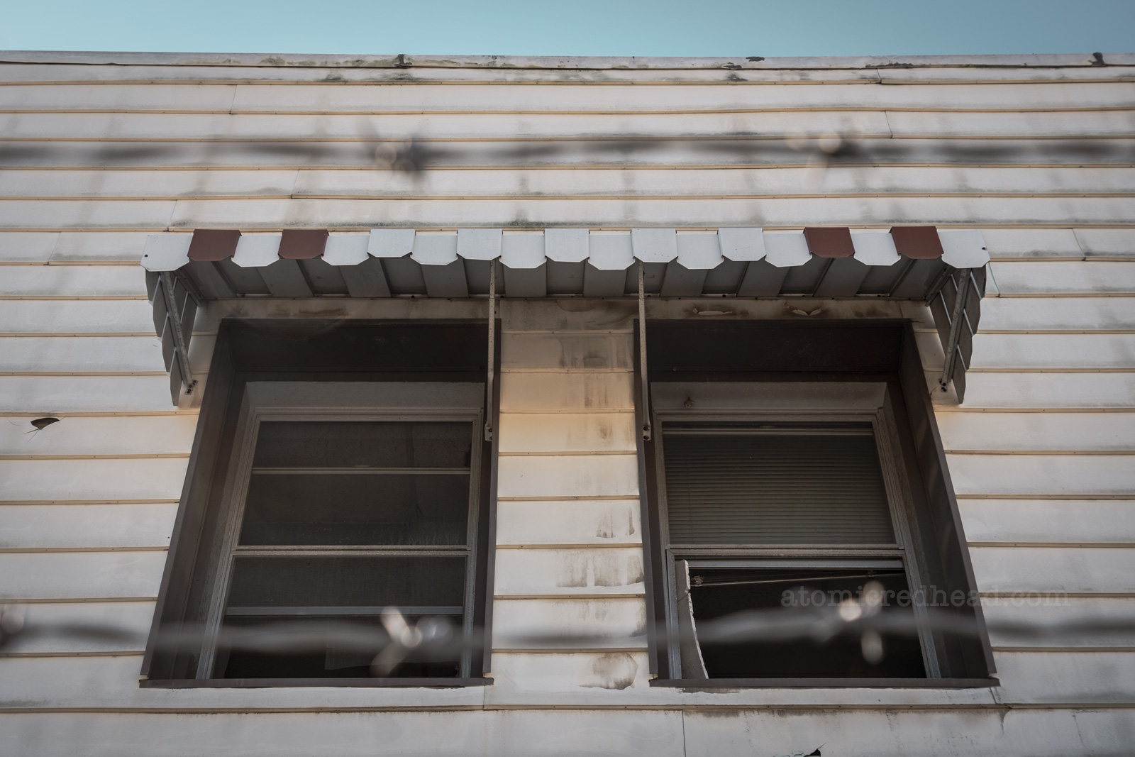 A broken out window under a metal awning.