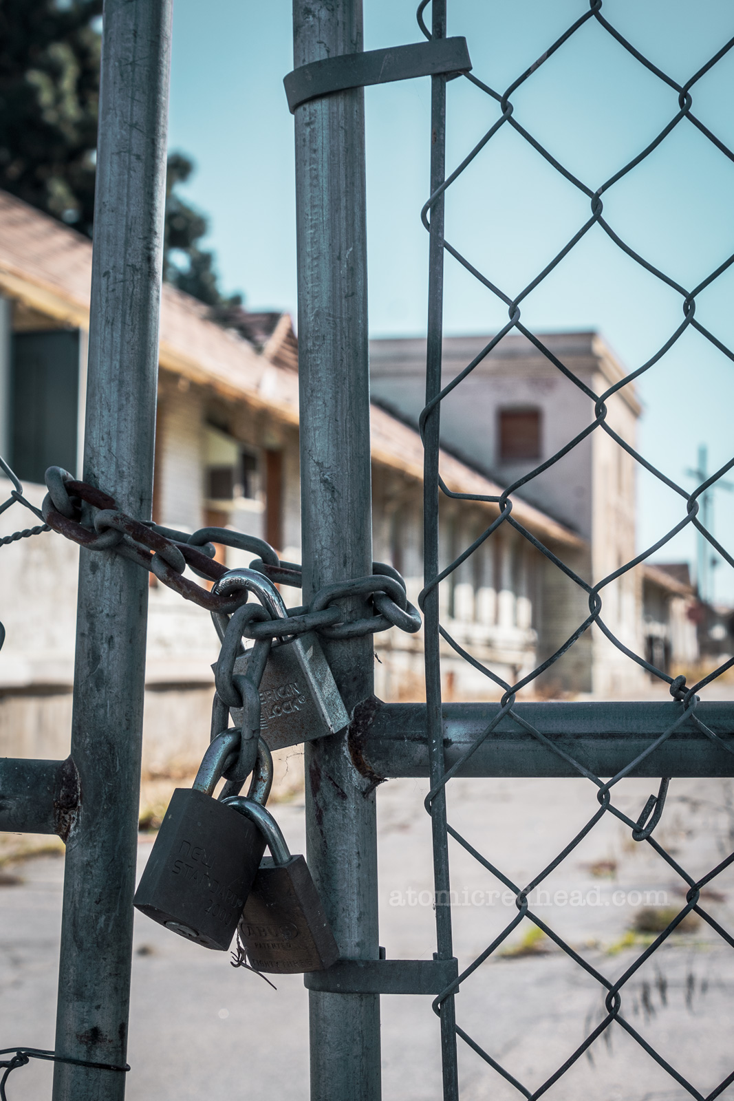 Three padlocks keep a chainlink gate closed.