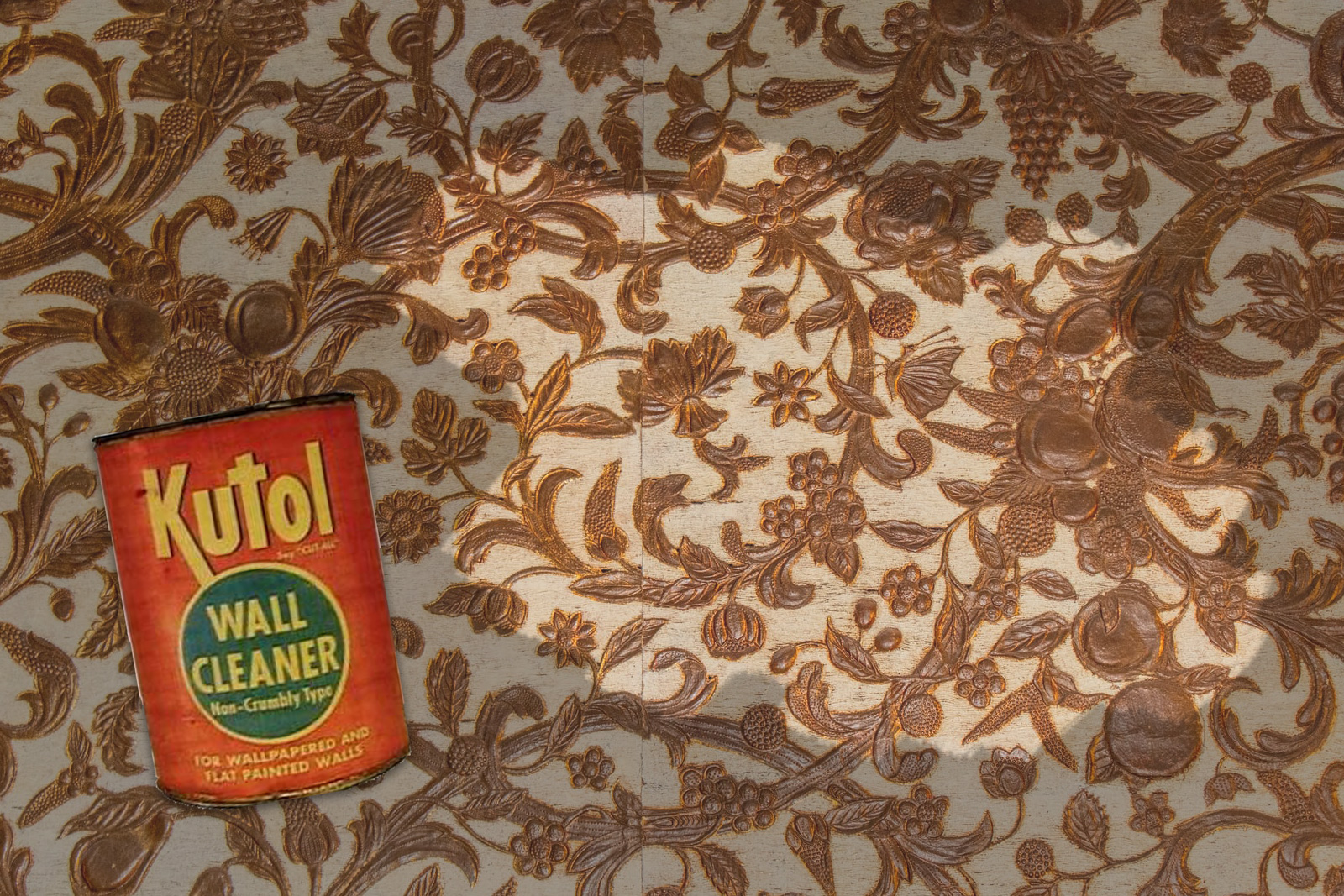 A white and gold wallpaper is marred by black soot, a small patch has been wiped away to make it clean. A red and green can of Kutol Wall Cleaner sits in the lower left croner.