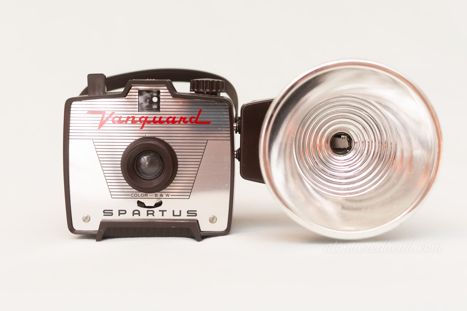 Partus Vanguard. A small brown square camera with a silver plate on front, and red script reading "Vanguard" and a flash attachment on the right.