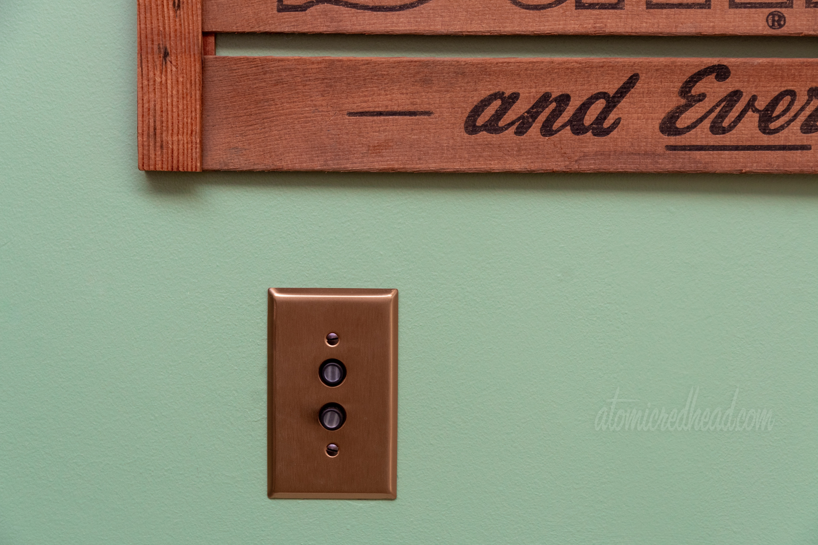 Close-up of our push button light switches, which are surrounded by a copper colored plate.