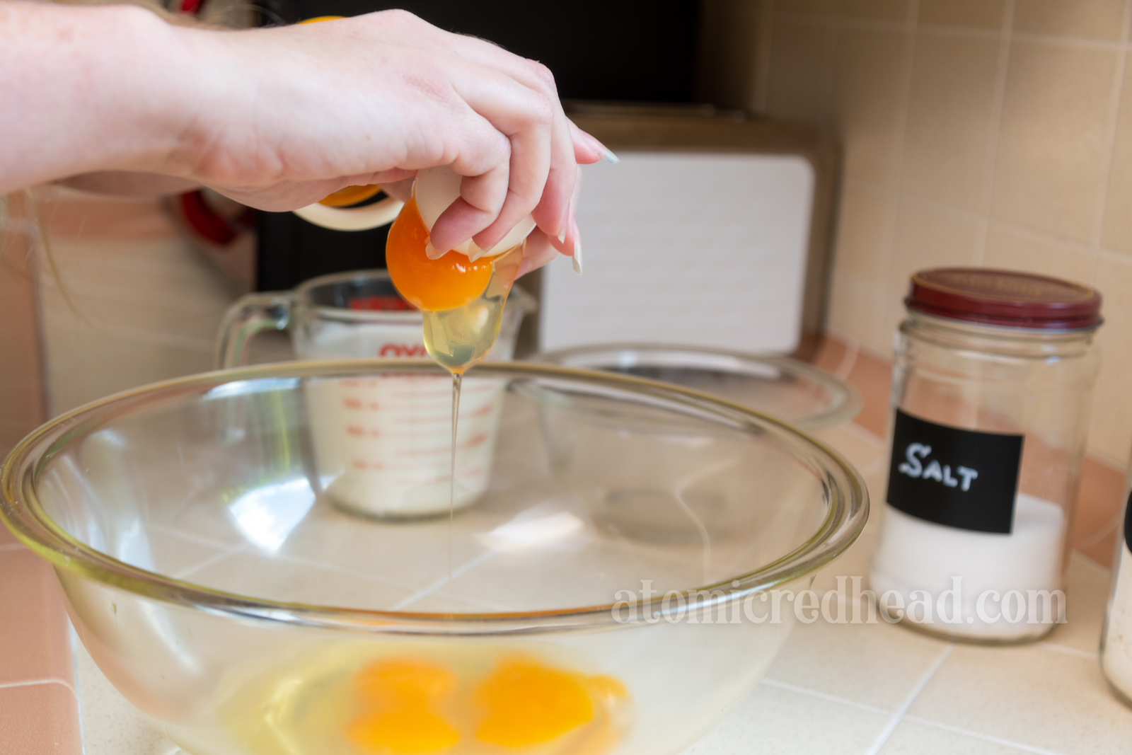 Close-up of my hand cracking an egg into a bowl.
