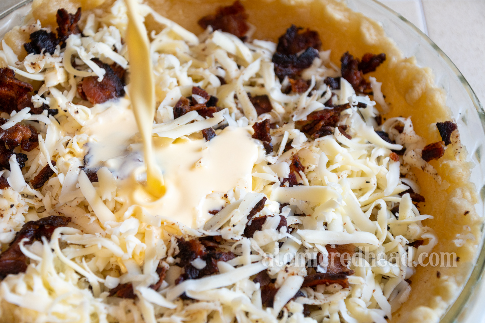 Pouring the egg and cream mixture into the cheese and bacon.