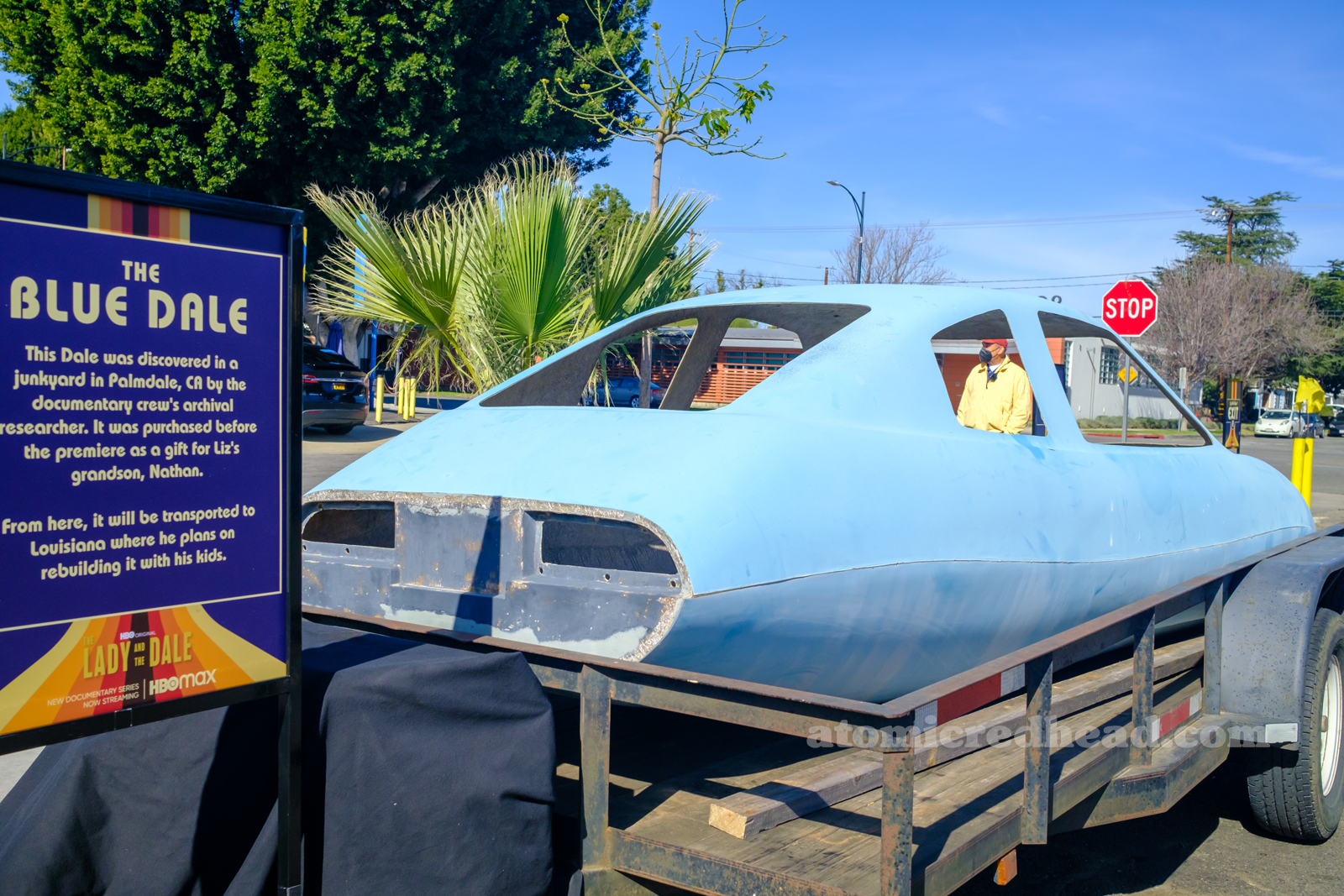 A blue fiberglass body of a Dale, a sign next to it reads "The Blue Dale - This Dale was discovered in a junkyard in Palmdale, CA by the documentary crew's archival researcher. It was purchased before the premier as a gift for Liz's grandson, Nathan. From here, it will be transported to Louisiana where he plans on rebuilding it with his kids."