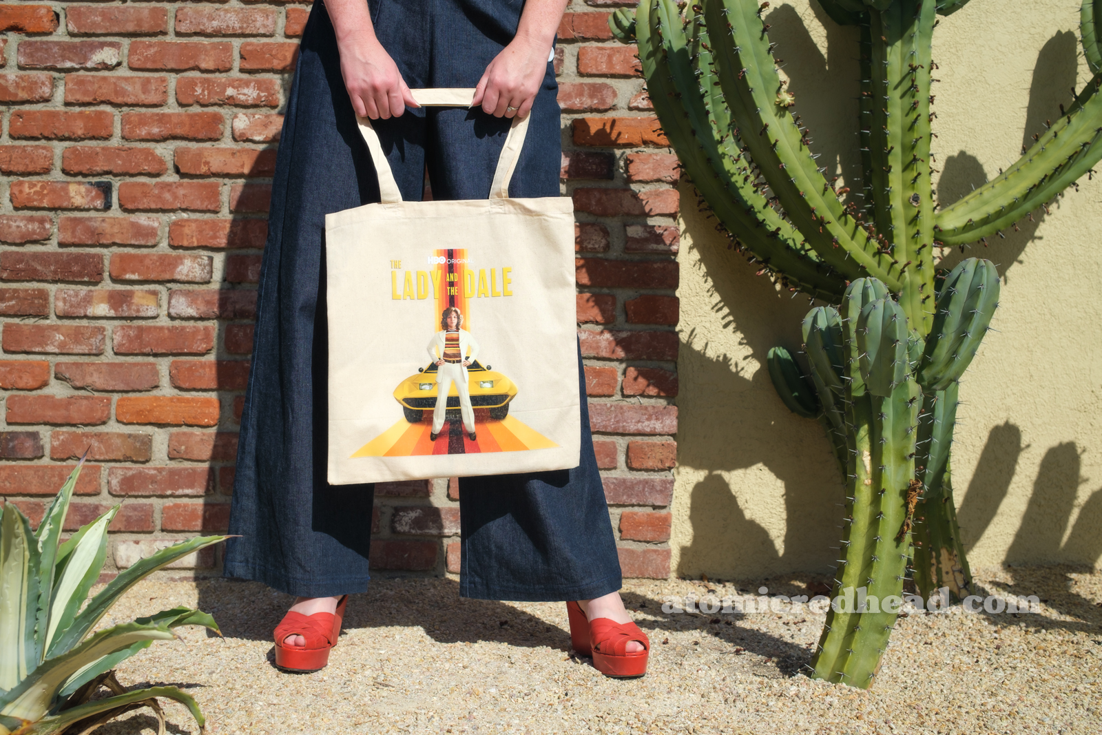 Close-up of the the swag bag, which features Liz standing in front of a yellow Dale, with yellow text reading "The Lady and the Dale"