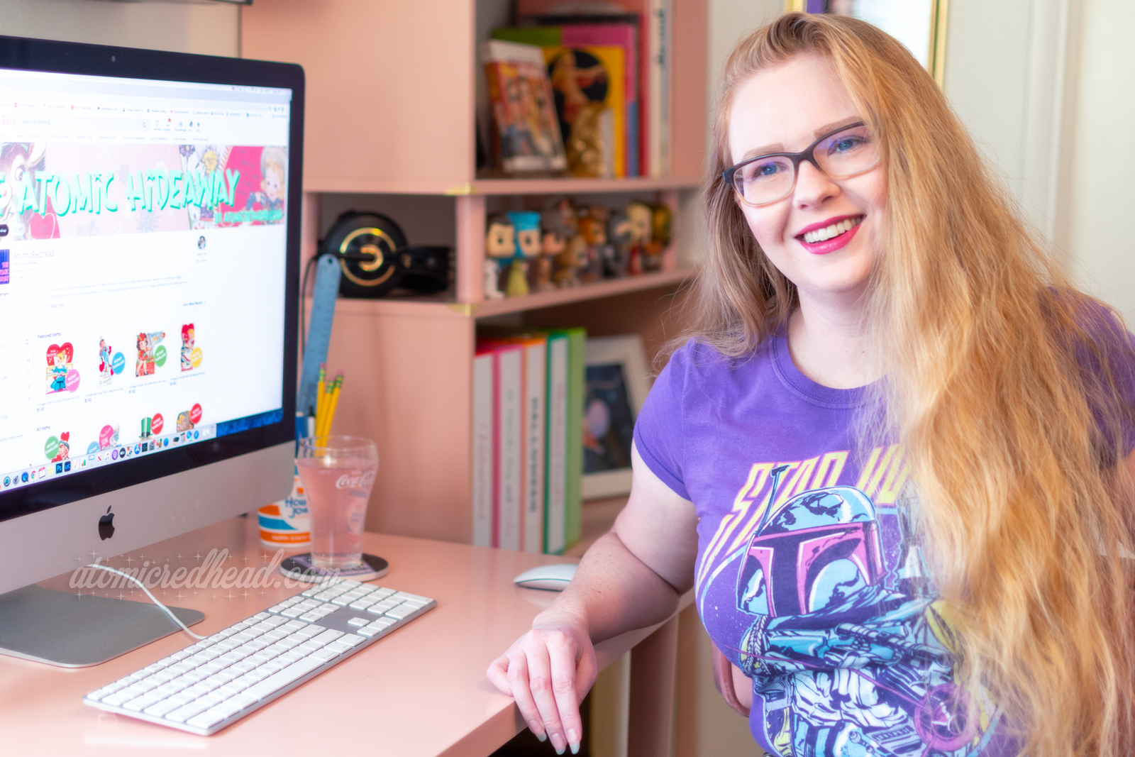 Myself seated at my desk, wearing a purple Boba Fett shirt. My Etsy shop visitable on my screen.