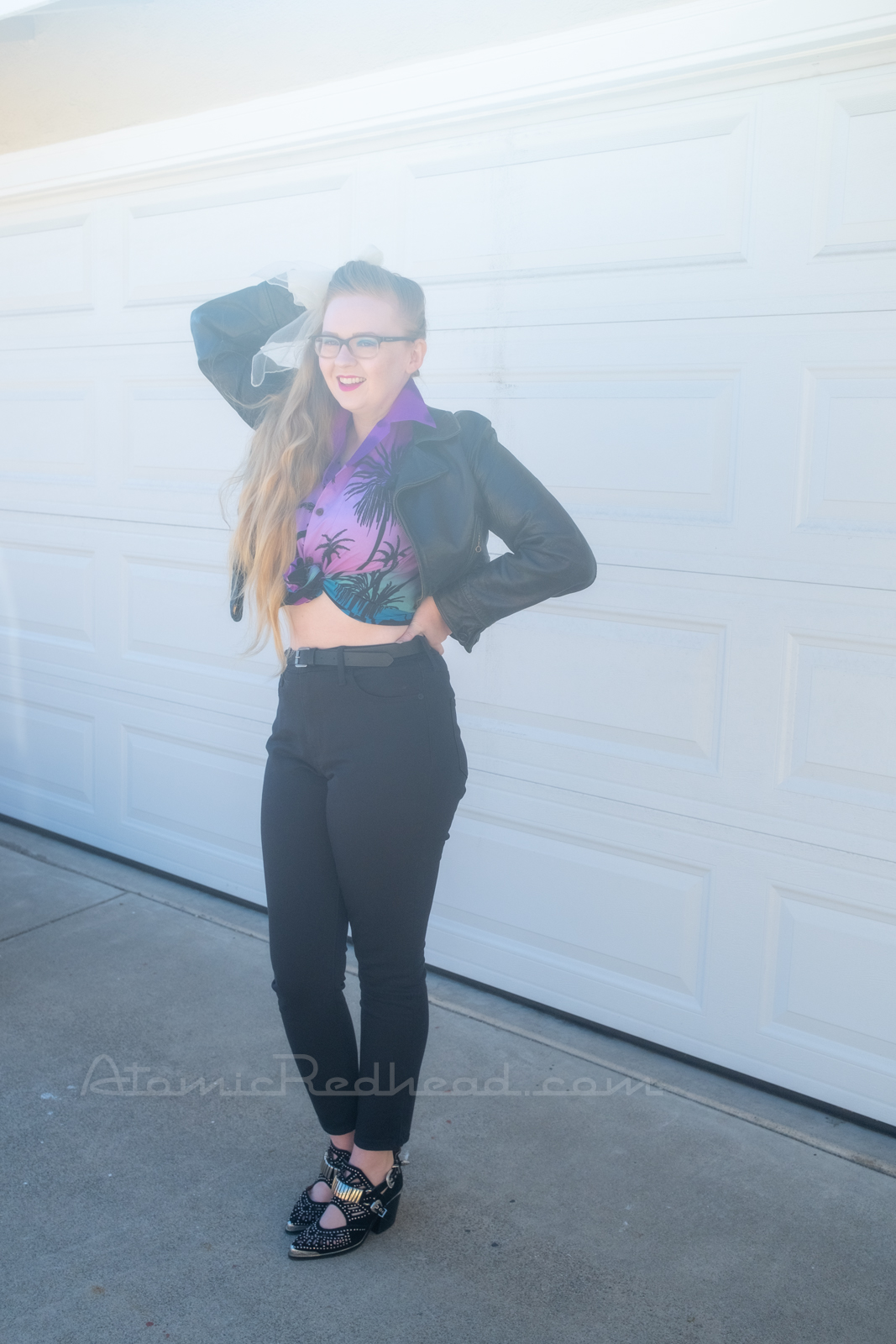 Myself standing in front of our garage door, wearing a black leather motorcycle jacket, purple and teal Hawaiian shirt, and black jeans.