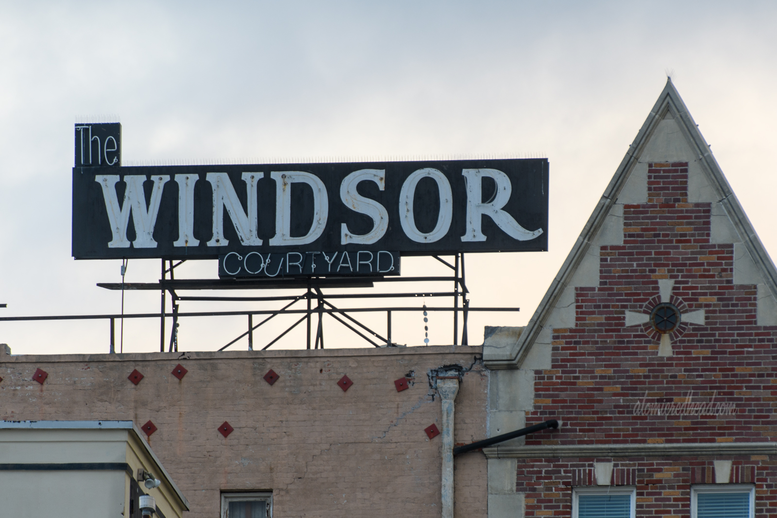 Atop an old English style brick building is a neon sign reading "The Windsor Courtyard"